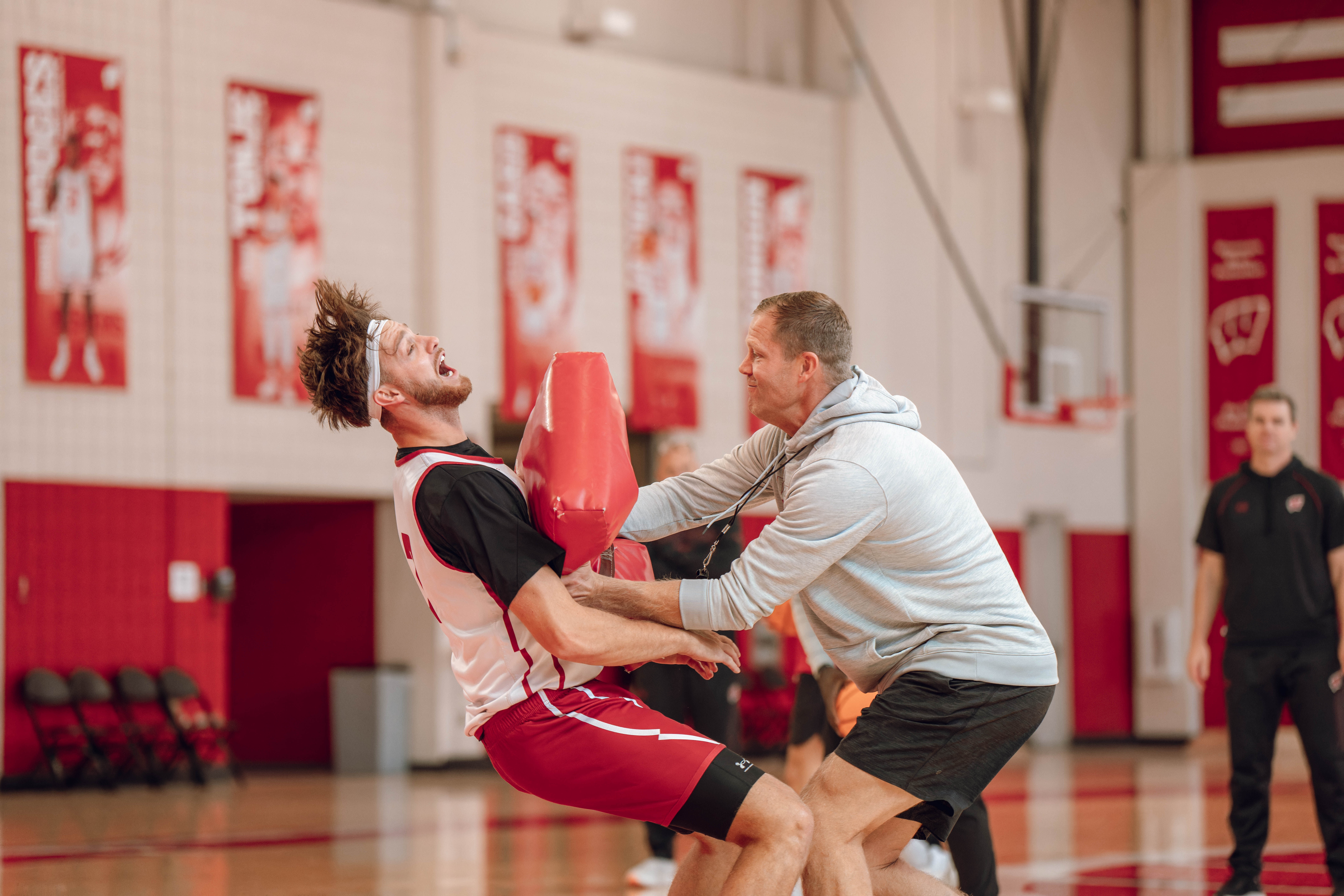 Wisconsin Badgers Associate Head Coach Joe Krabbenhoft hits forward Carter Gilmore #7 during a drill at the Nicholas Johnson Pavilion on October 7, 2024 in Madison, WI. Photography by Ross Harried for Second Crop Sports.