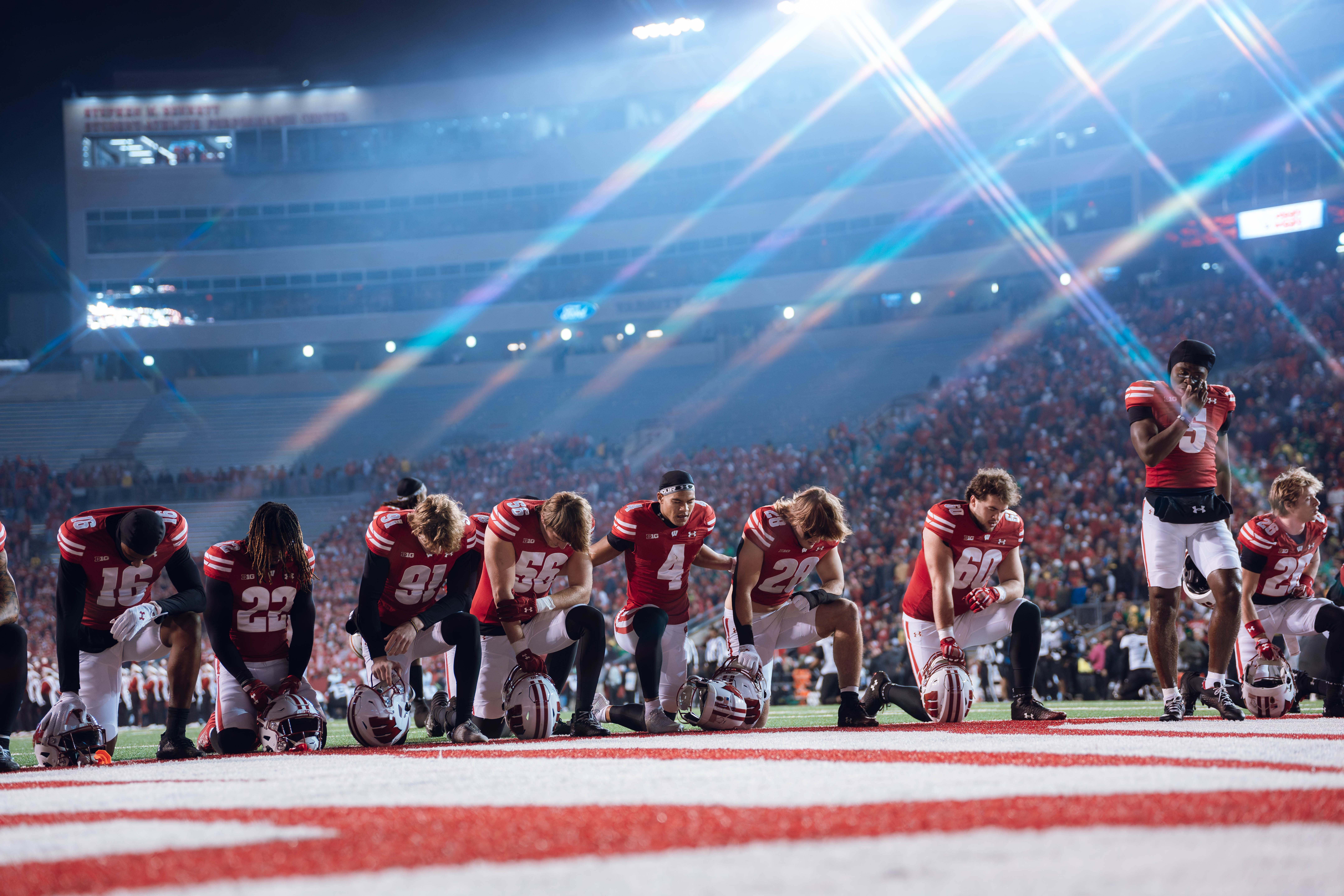 Wisconsin Badgers take a knee prior to kickoff. Wisconsin Badgers vs. Oregon Ducks at Camp Randall Stadium on November 16, 2024 in Madison, Wisconsin. Photography by Ross Harried for Second Crop Sports.