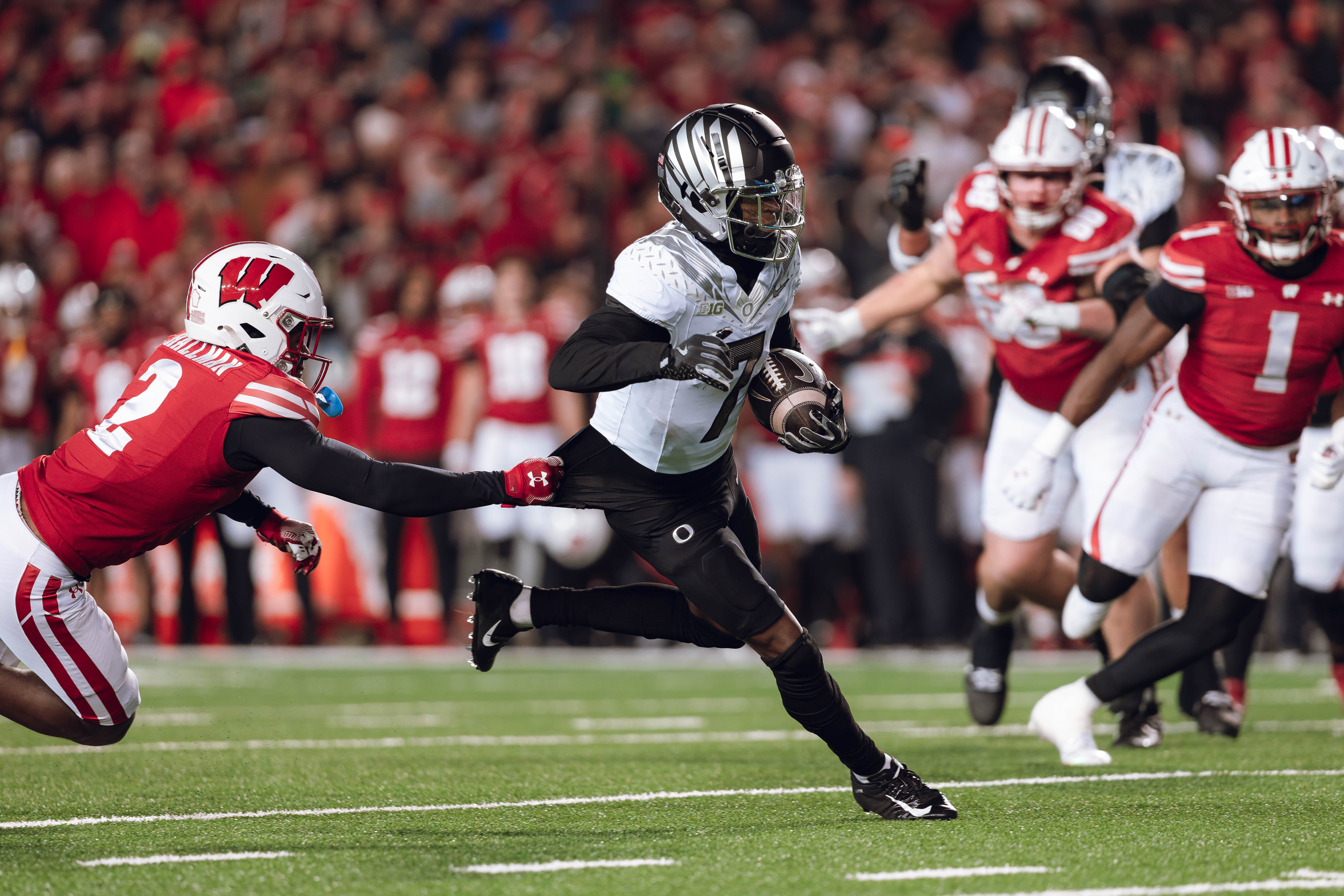 Oregon wide receiver Evan Stewart #7 escapes the clutches of Wisconsin Badgers cornerback Ricardo Hallman #2 at Camp Randall Stadium on November 16, 2024 in Madison, Wisconsin. Photography by Ross Harried for Second Crop Sports.