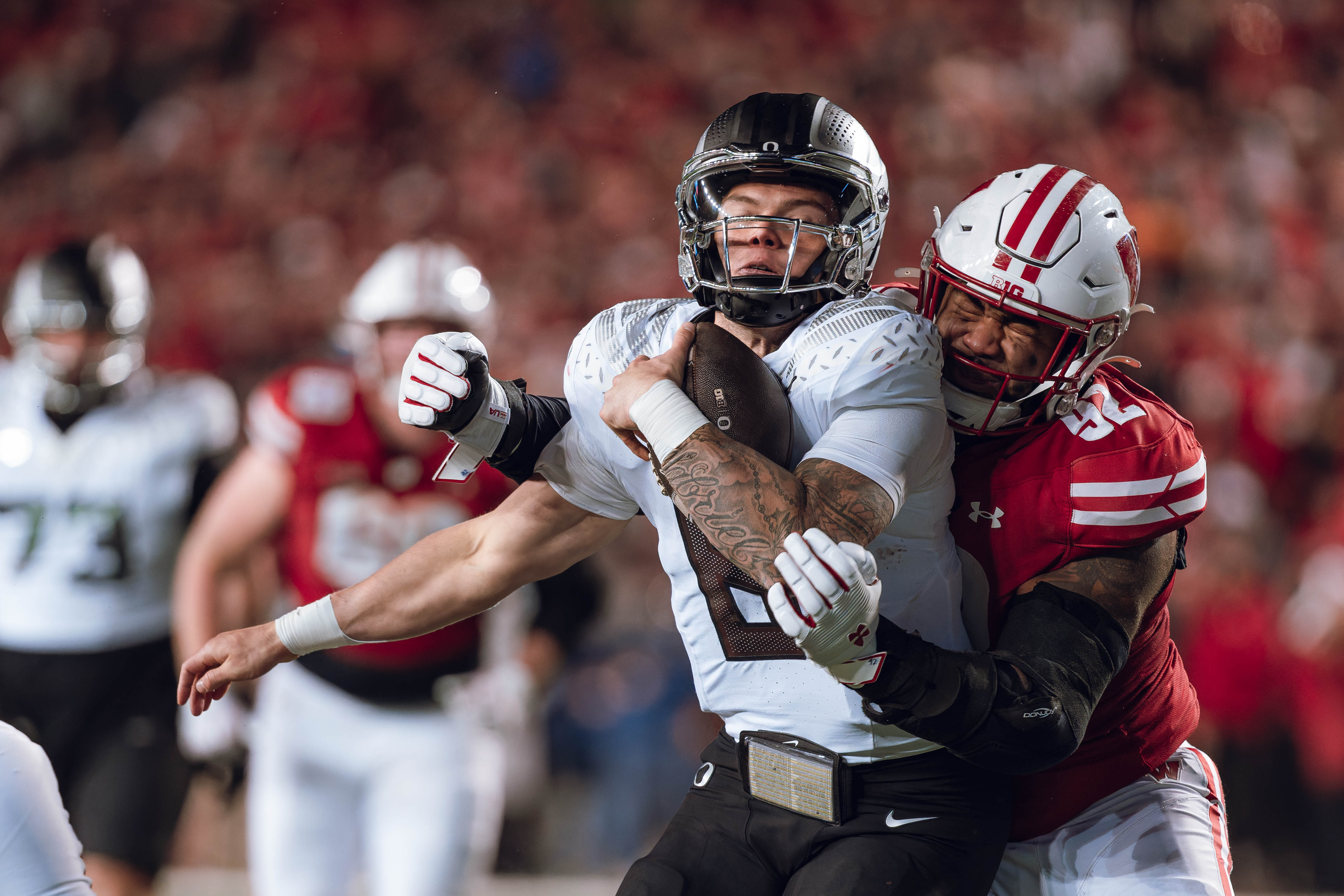 Oregon quarterback Dillon Gabriel #8 gets tackled by Wisconsin Badgers defensive lineman Curt Neal #92 at Camp Randall Stadium on November 16, 2024 in Madison, Wisconsin. Photography by Ross Harried for Second Crop Sports.