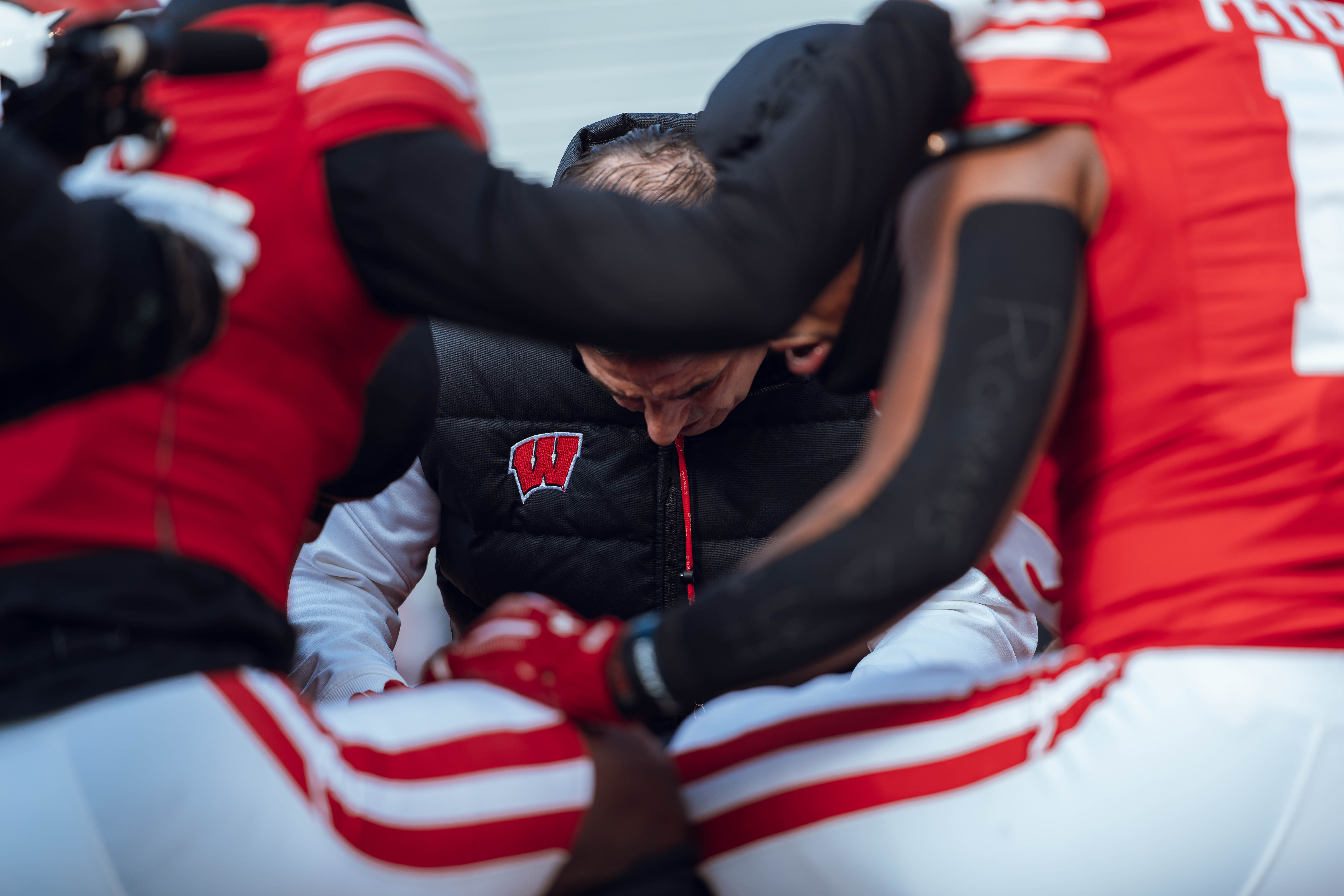 Wisconsin Badgers Head Coach Luke Fickell takes a knee with his team before the Wisconsin Badgers take on the Minnesota Golden Gophers at Camp Randall Stadium on November 29, 2024 in Madison, Wisconsin. Photography by Ross Harried for Second Crop Sports.