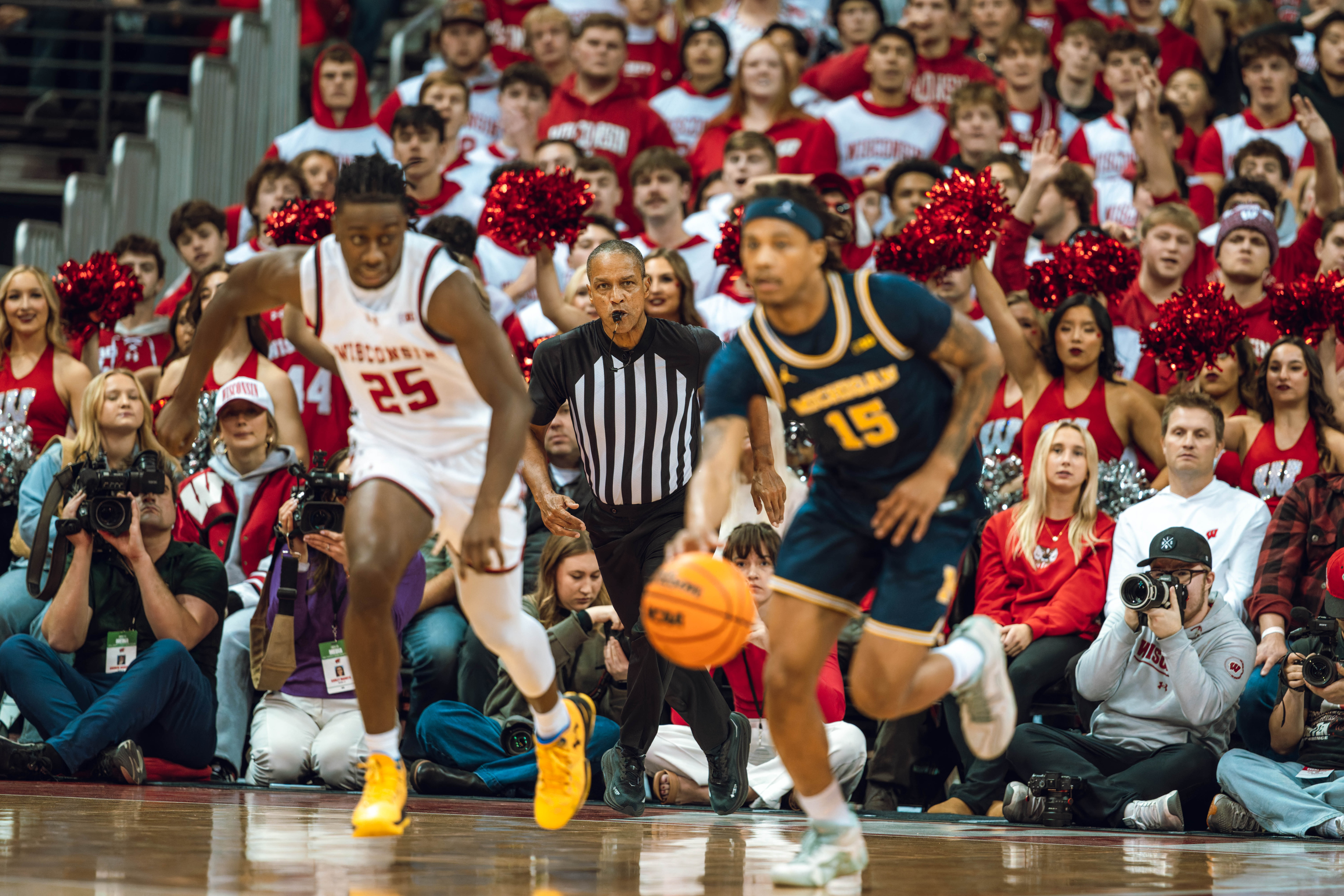 Wisconsin Badgers guard John Blackwell #25 chases Michigan Wolverines guard Rubin Jones #15 as the referee looks on at the Kohl Center on December 03, 2024 in Madison, Wisconsin. Photography by Ross Harried for Second Crop Sports.