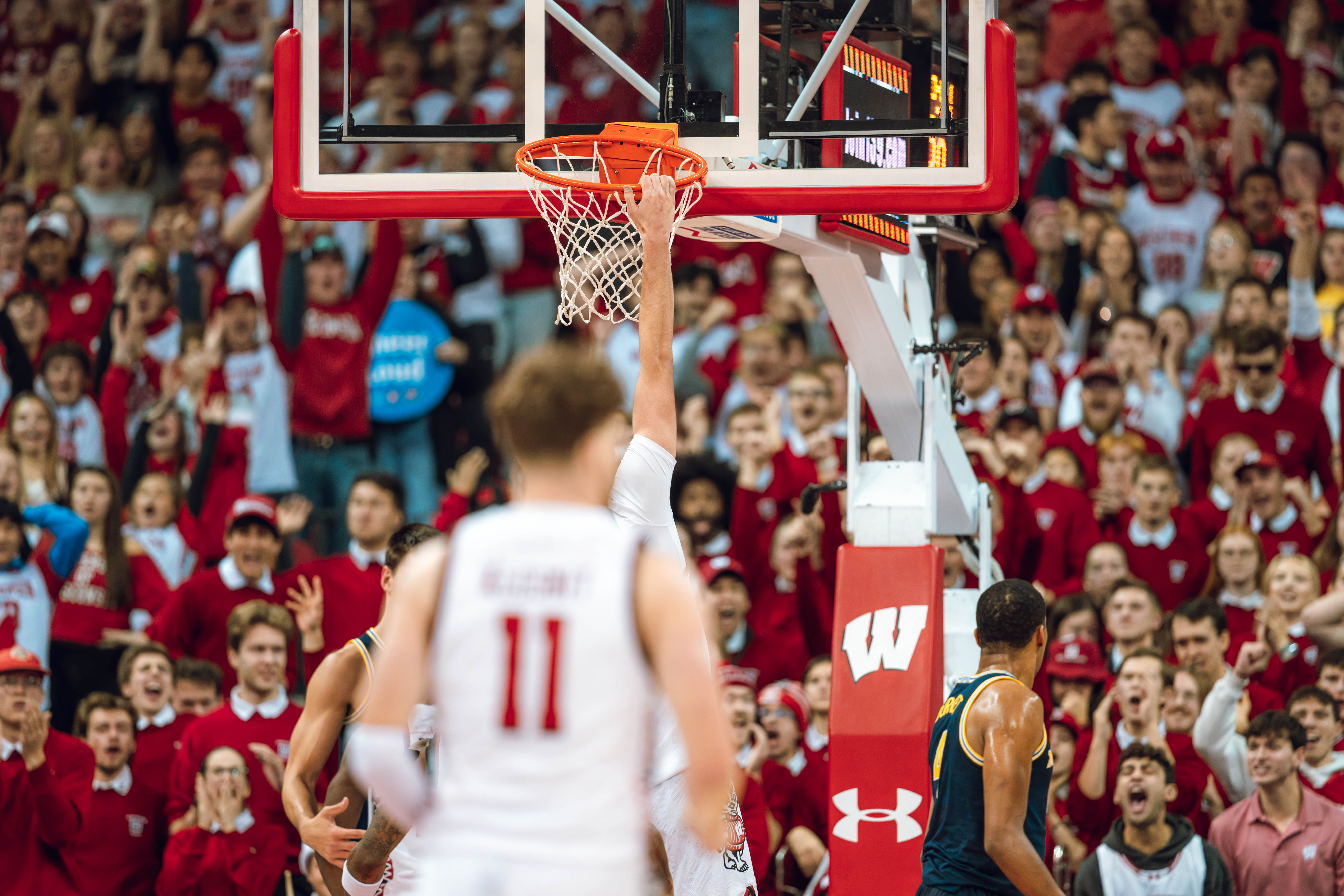 Wisconsin Badgers forward Nolan Winter #31 hangs from the rim after dunking against the Michigan Wolverines at the Kohl Center on December 03, 2024 in Madison, Wisconsin. Photography by Ross Harried for Second Crop Sports.