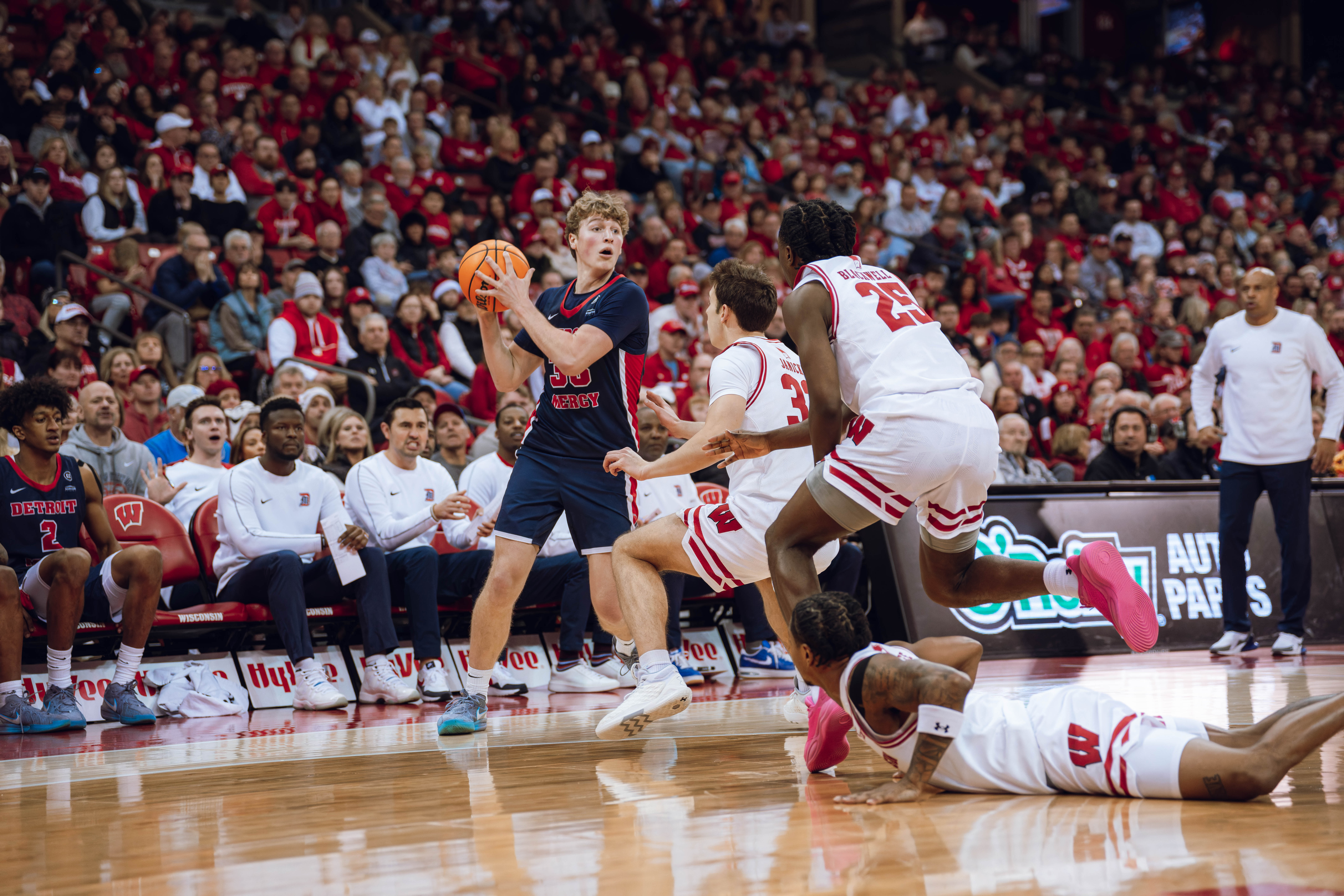 Detroit Mercy Titans guard TJ Nadeau #33 surveys the court while three Badger players rush out to guard him at Kohl Center on December 22, 2024 in Madison, Wisconsin. Photography by Ross Harried for Second Crop Sports.