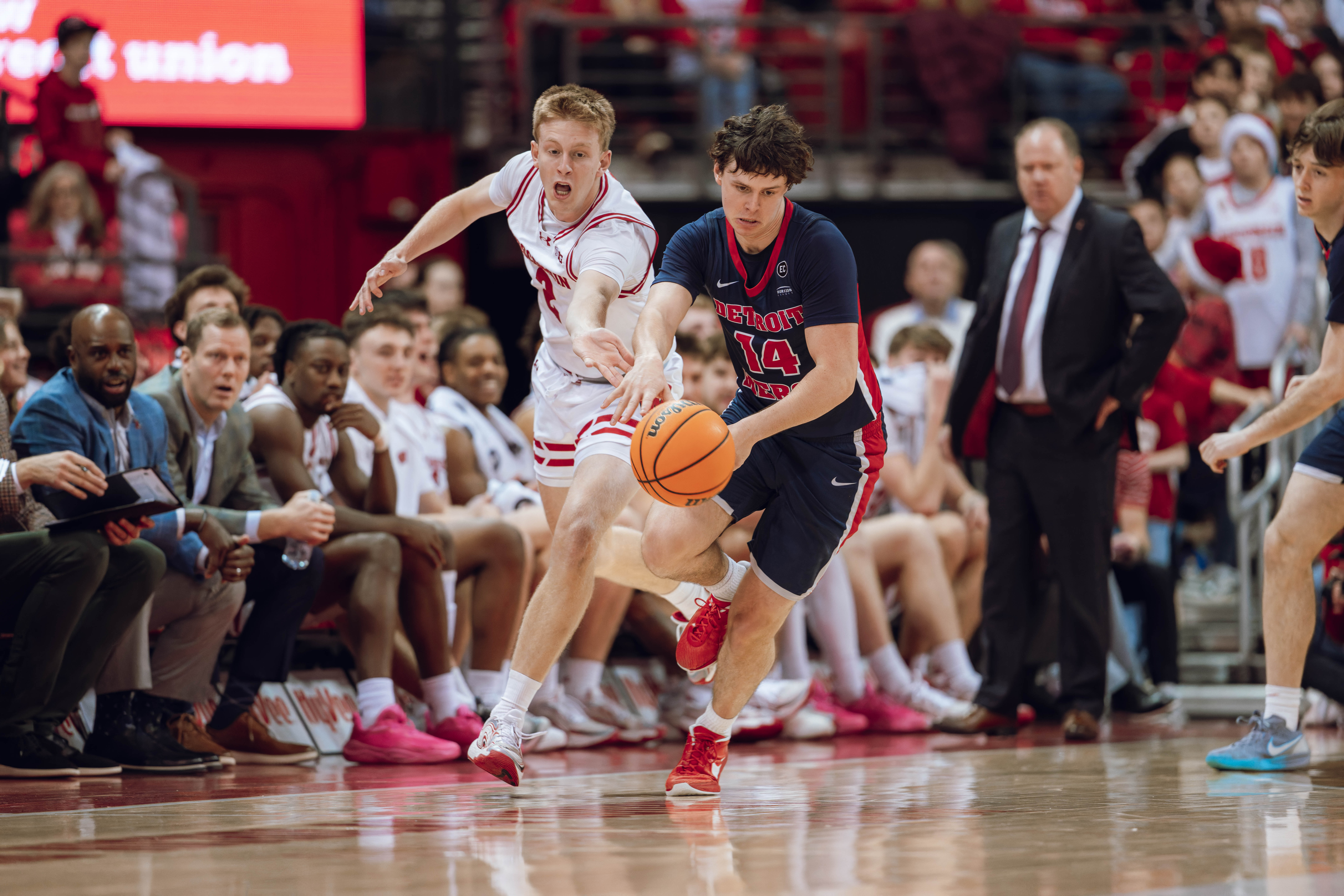 Detroit Mercy Titans guard Peter Fuchs Jr. #14 chases down a loose ball against the Wisconsin Badgers at Kohl Center on December 22, 2024 in Madison, Wisconsin. Photography by Ross Harried for Second Crop Sports.