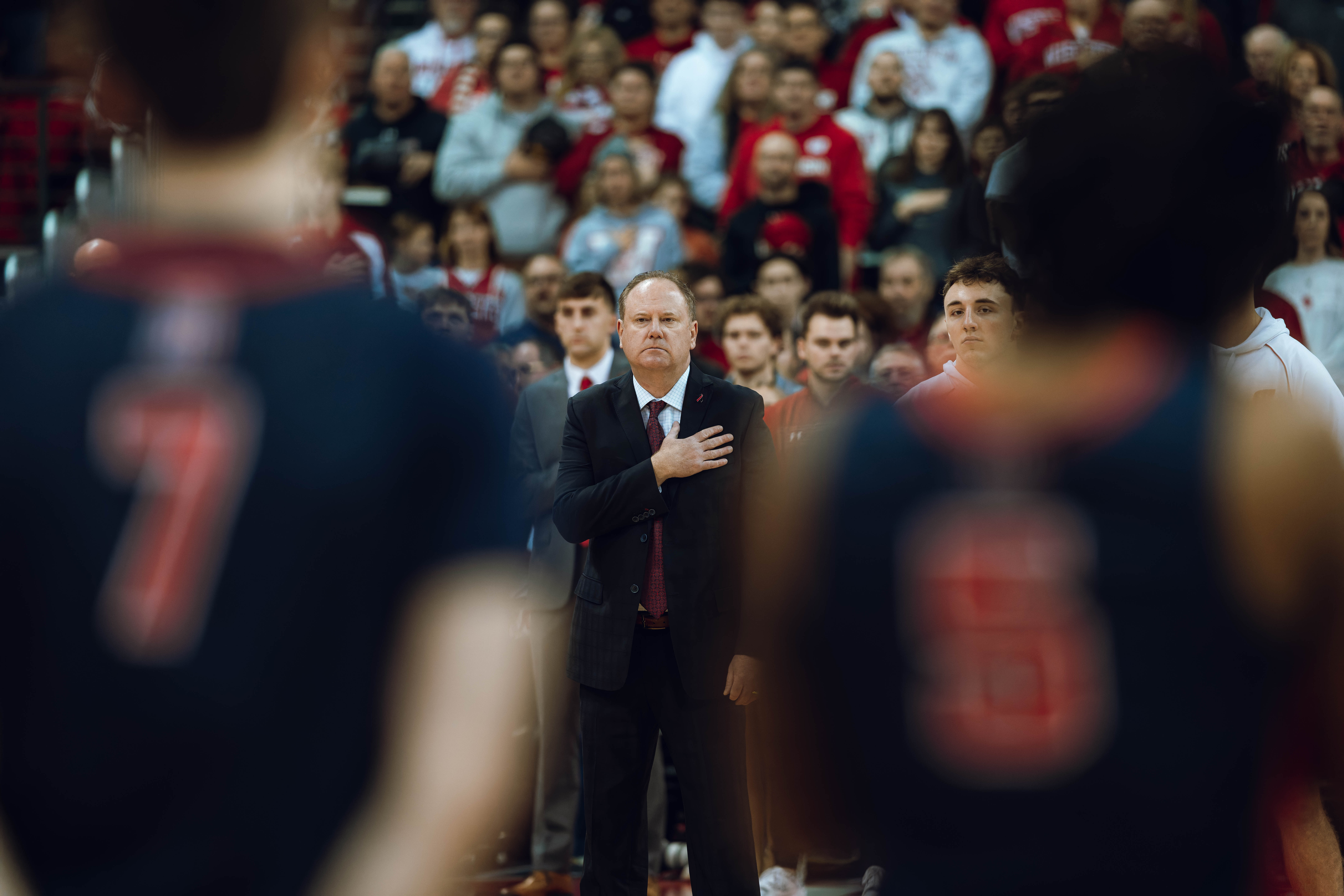 Wisconsin Badgers Head Coach Greg Gard places his hand over his heart during the nation anthem against the Detroit Mercy Titans at Kohl Center on December 22, 2024 in Madison, Wisconsin. Photography by Ross Harried for Second Crop Sports.