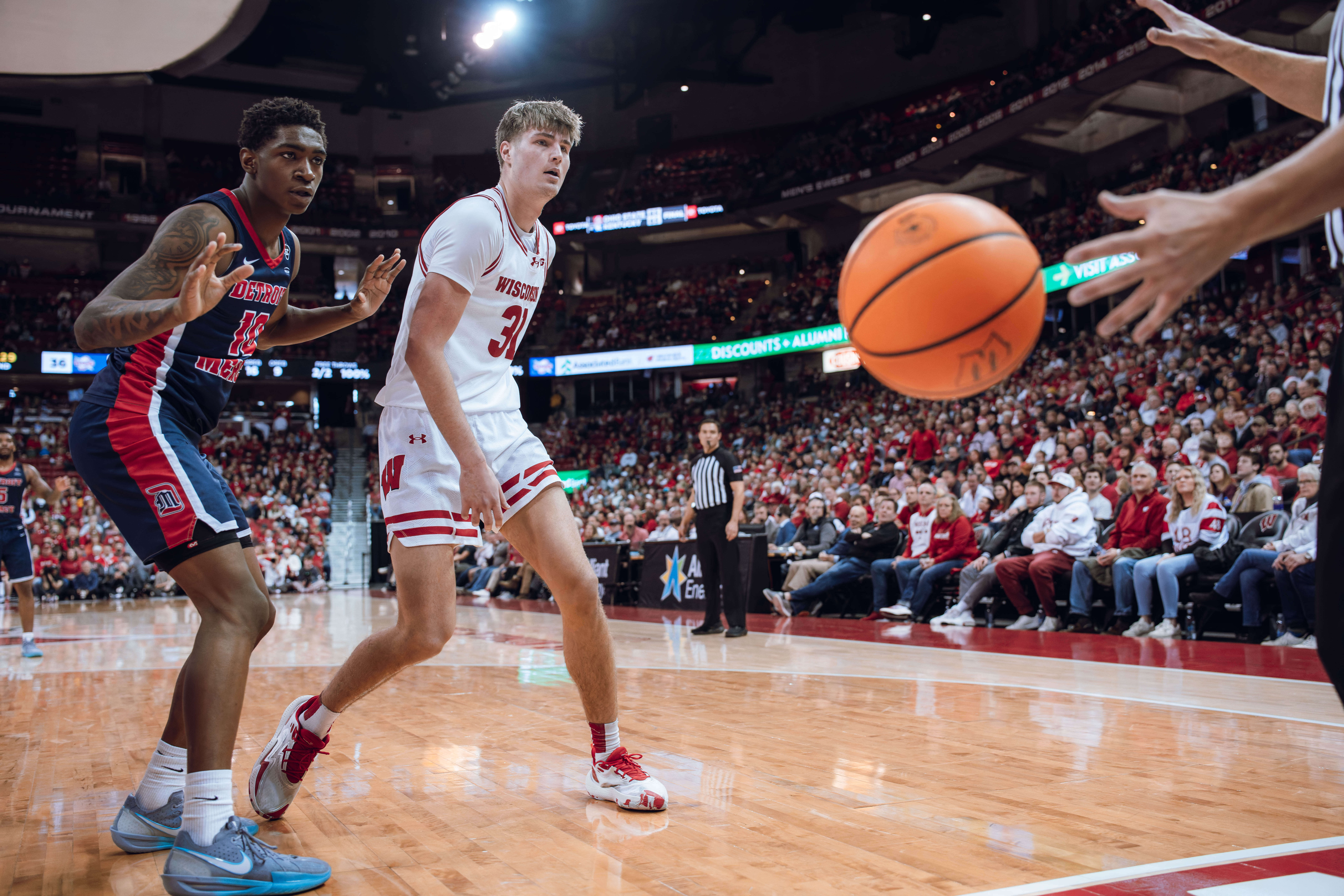 Detroit Mercy Titans guard Nate Johnson #10 and Wisconsin Badgers forward Nolan Winter #31 both look to the referee at Kohl Center on December 22, 2024 in Madison, Wisconsin. Photography by Ross Harried for Second Crop Sports.