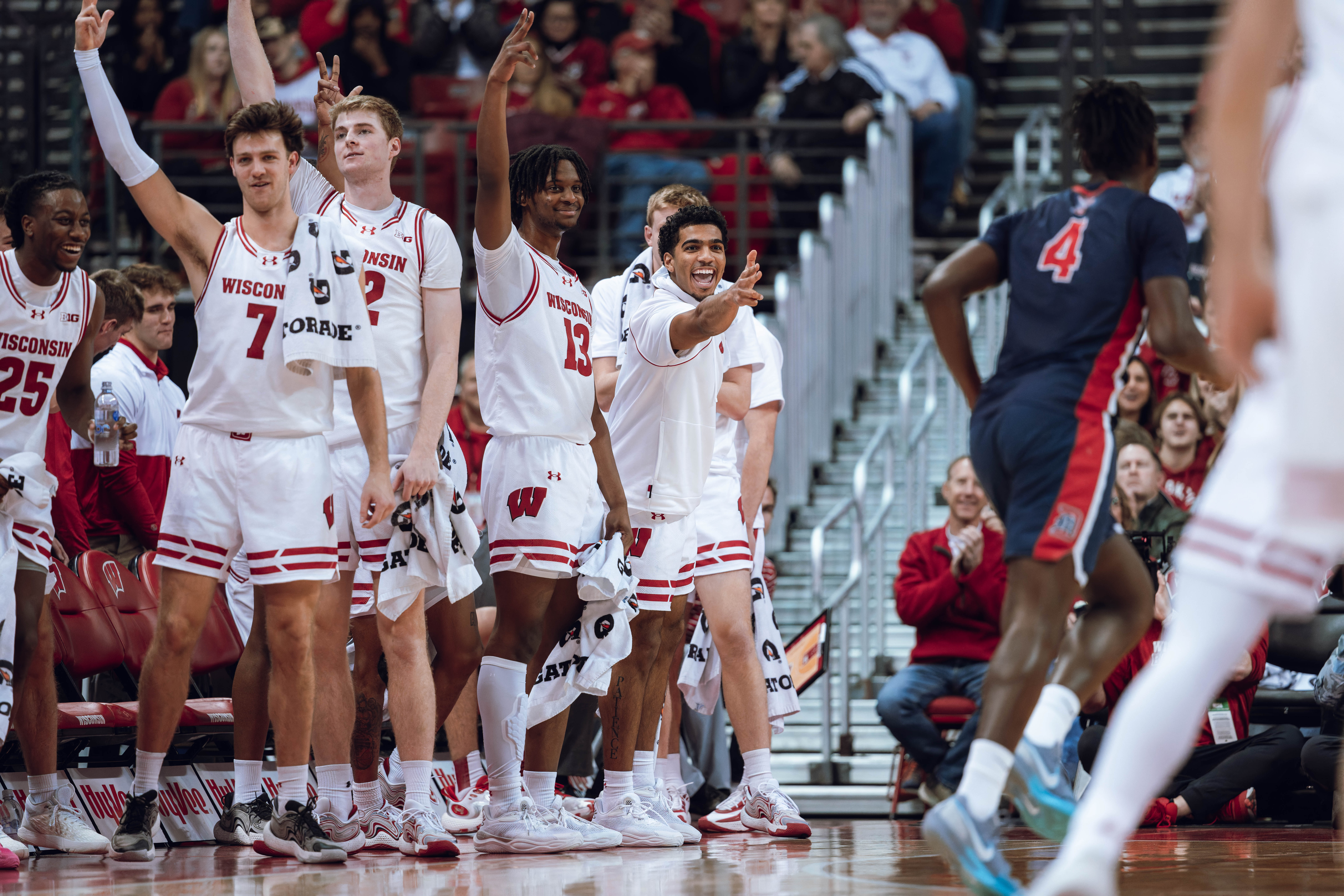 Wisconsin Badgers Carter Gilmore #7, Steven Crowl #22, Xavier Amos #13 and Daniel Freitag (center) celebrate a 3-pointer against the Detroit Mercy Titans at Kohl Center on December 22, 2024 in Madison, Wisconsin. Photography by Ross Harried for Second Crop Sports.