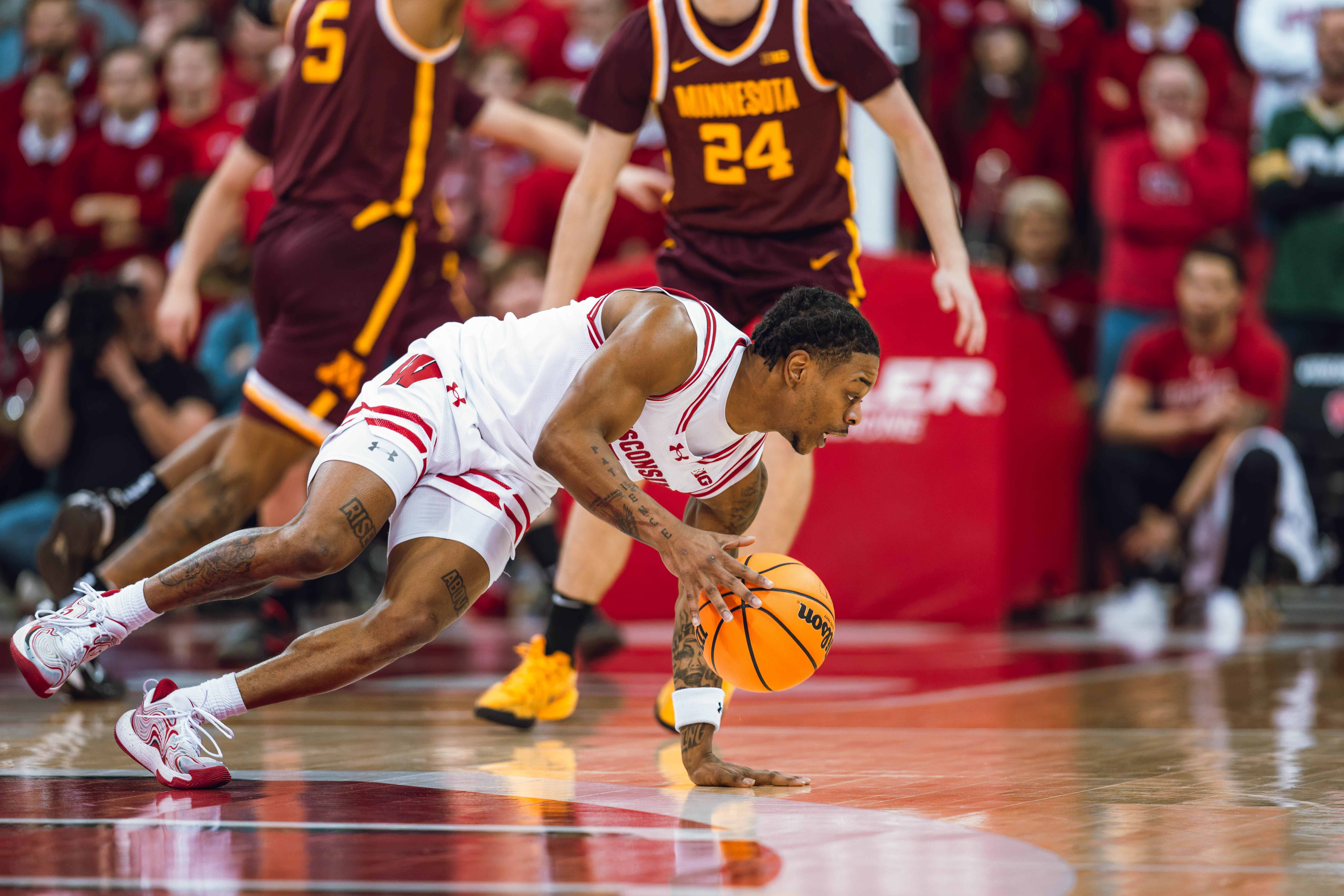 Wisconsin Badgers guard Kamari McGee #4 maintains his dribble despite falling against the Minnesota Golden Gophers at Kohl Center on January 10, 2025 in Madison, Wisconsin. Photography by Ross Harried for Second Crop Sports.