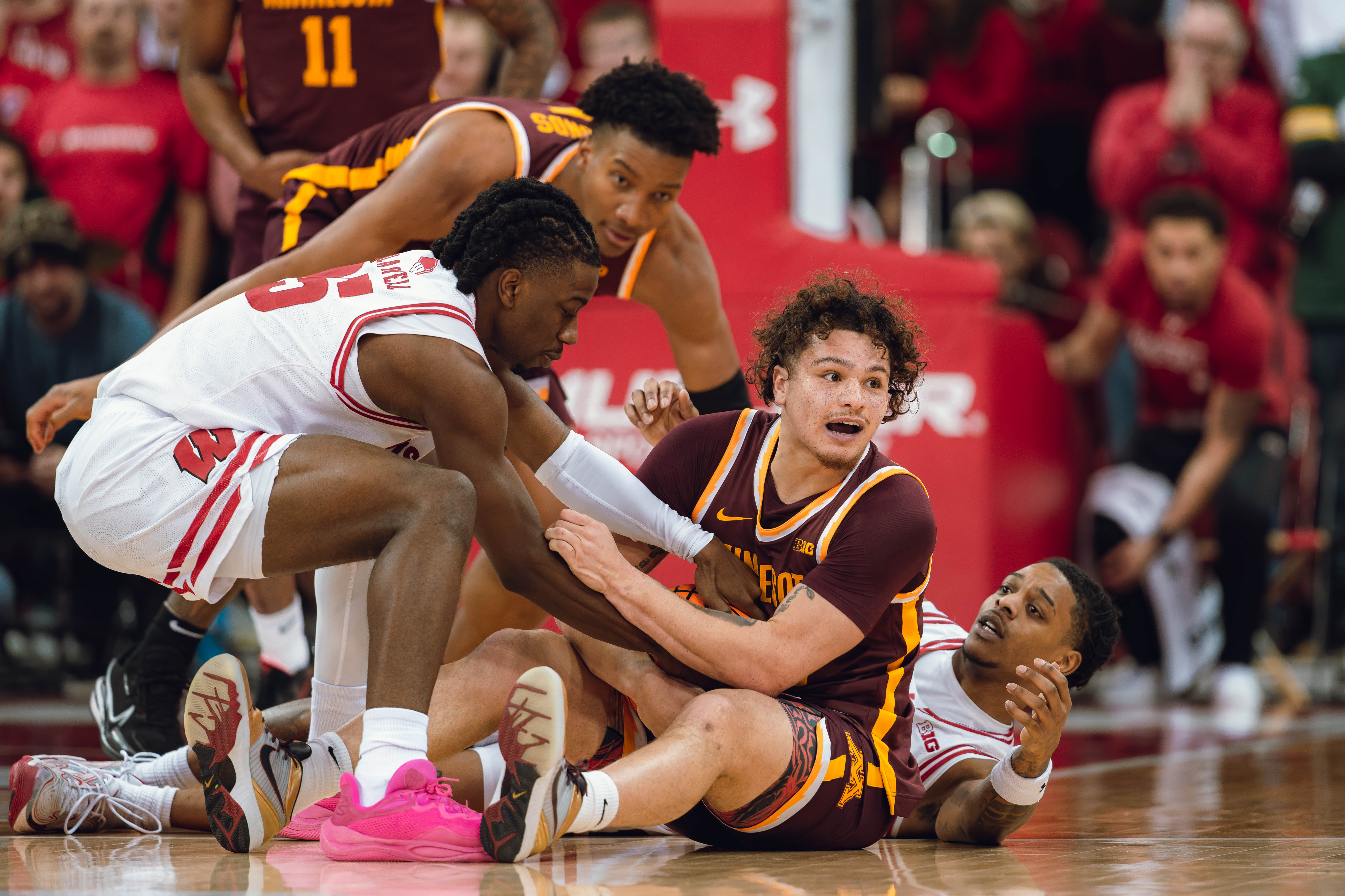 Wisconsin Badgers guard John Blackwell #25 (left) ties up the ball with Minnesota Golden Gophers guard Lu'Cye Patterson #25 (center) as Wisconsin Badgers guard Kamari McGee #4 (right) looks on at Kohl Center on January 10, 2025 in Madison, Wisconsin. Photography by Ross Harried for Second Crop Sports.