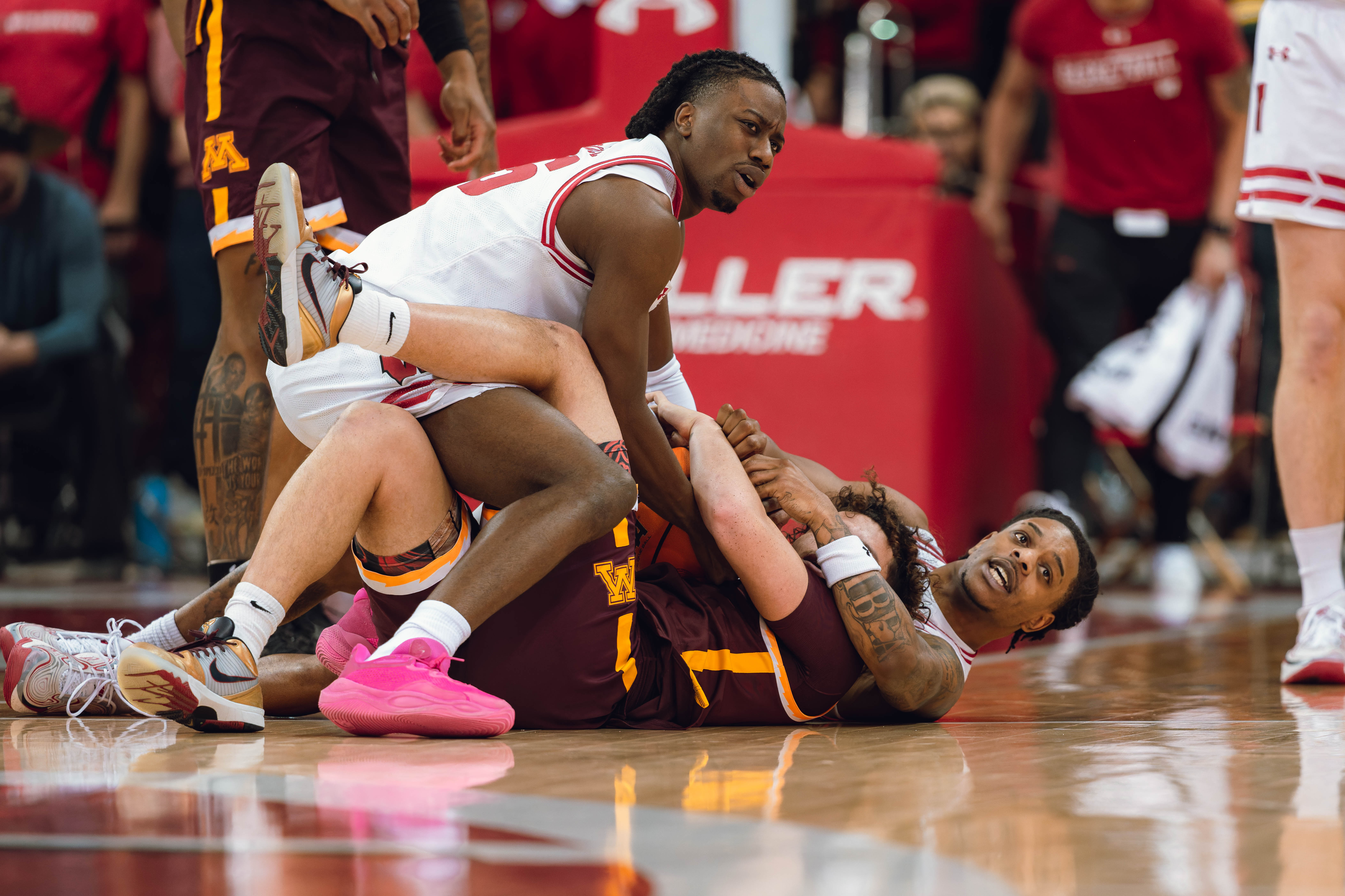 Wisconsin Badgers guard John Blackwell #25 (left) ties up the ball with Minnesota Golden Gophers guard Lu'Cye Patterson #25 (center) as Wisconsin Badgers guard Kamari McGee #4 (right) looks on at Kohl Center on January 10, 2025 in Madison, Wisconsin. Photography by Ross Harried for Second Crop Sports.