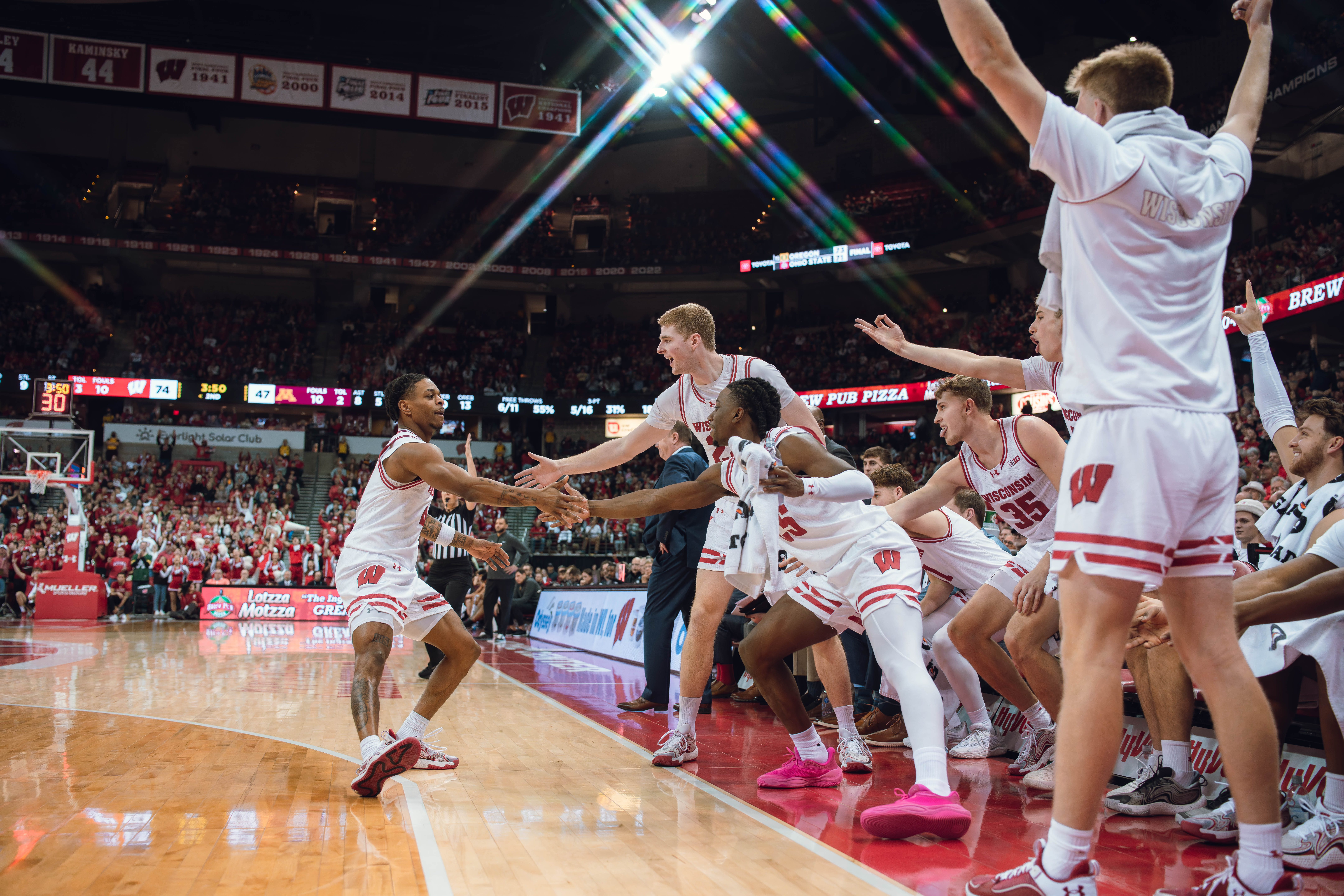 Wisconsin Badgers guard Kamari McGee #4 celebrates a three pointer with John Blackwell #25 and Steven Crowl #22 against the Minnesota Golden Gophers at Kohl Center on January 10, 2025 in Madison, Wisconsin. Photography by Ross Harried for Second Crop Sports.