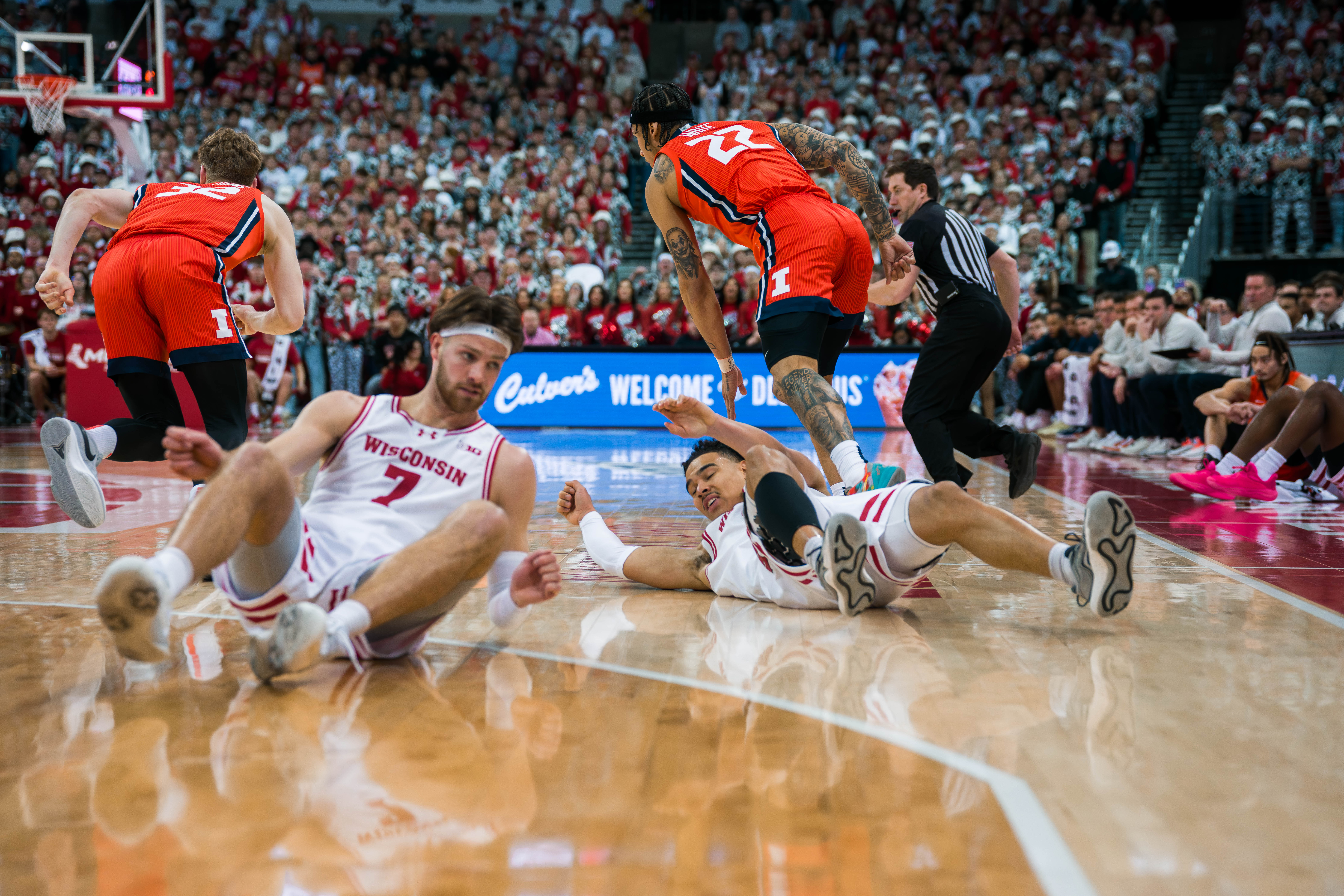 Wisconsin Badgers forward Carter Gilmore #7 and guard John Tonje #9 gather themselves after diving for a loose ball against the Illinois Fighting Illini at The Kohl Center on February 18, 2025 in Madison, Wisconsin. Photography by Ross Harried for Second Crop Sports.