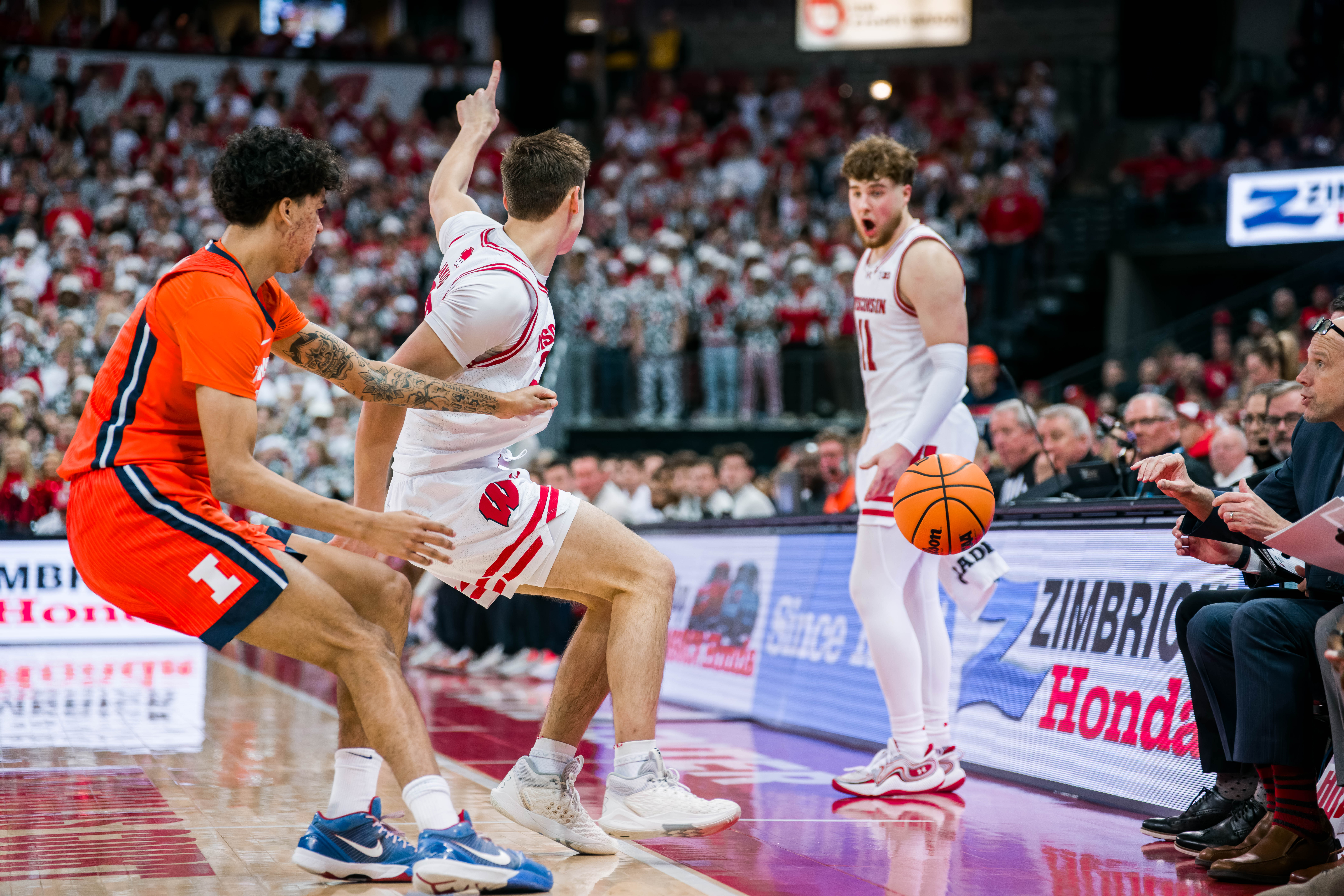 Wisconsin Badgers guard Max Klesmit #11 shows a surprised look as Wisconsin Badgers guard Jack Janicki #33 tries to signal for possession against the Illinois Fighting Illini at The Kohl Center on February 18, 2025 in Madison, Wisconsin. Photography by Ross Harried for Second Crop Sports.