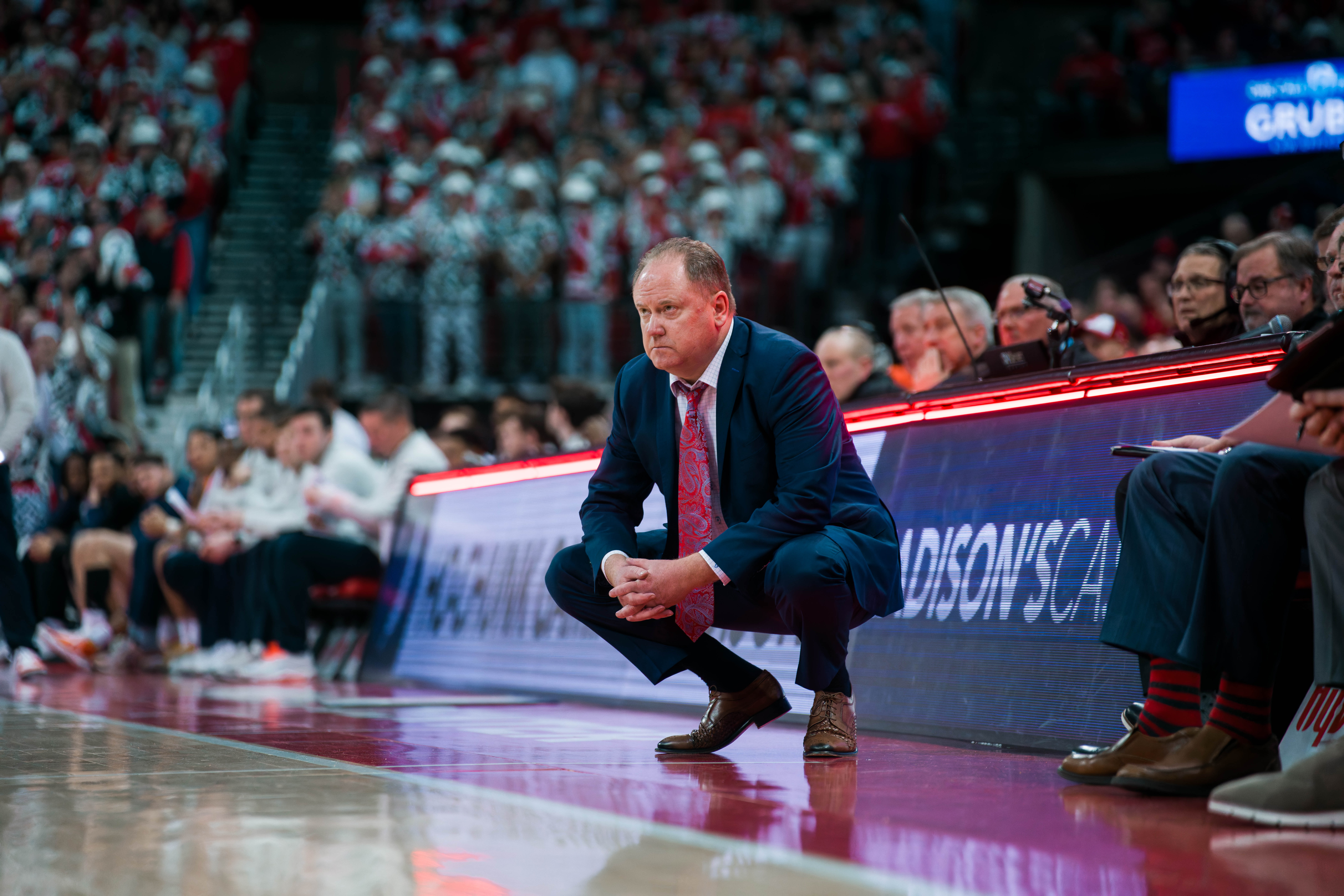 Wisconsin Badgers Head Coach Greg Gard squats down for a better angle during a game against the Illinois Fighting Illini at The Kohl Center on February 18, 2025 in Madison, Wisconsin. Photography by Ross Harried for Second Crop Sports.