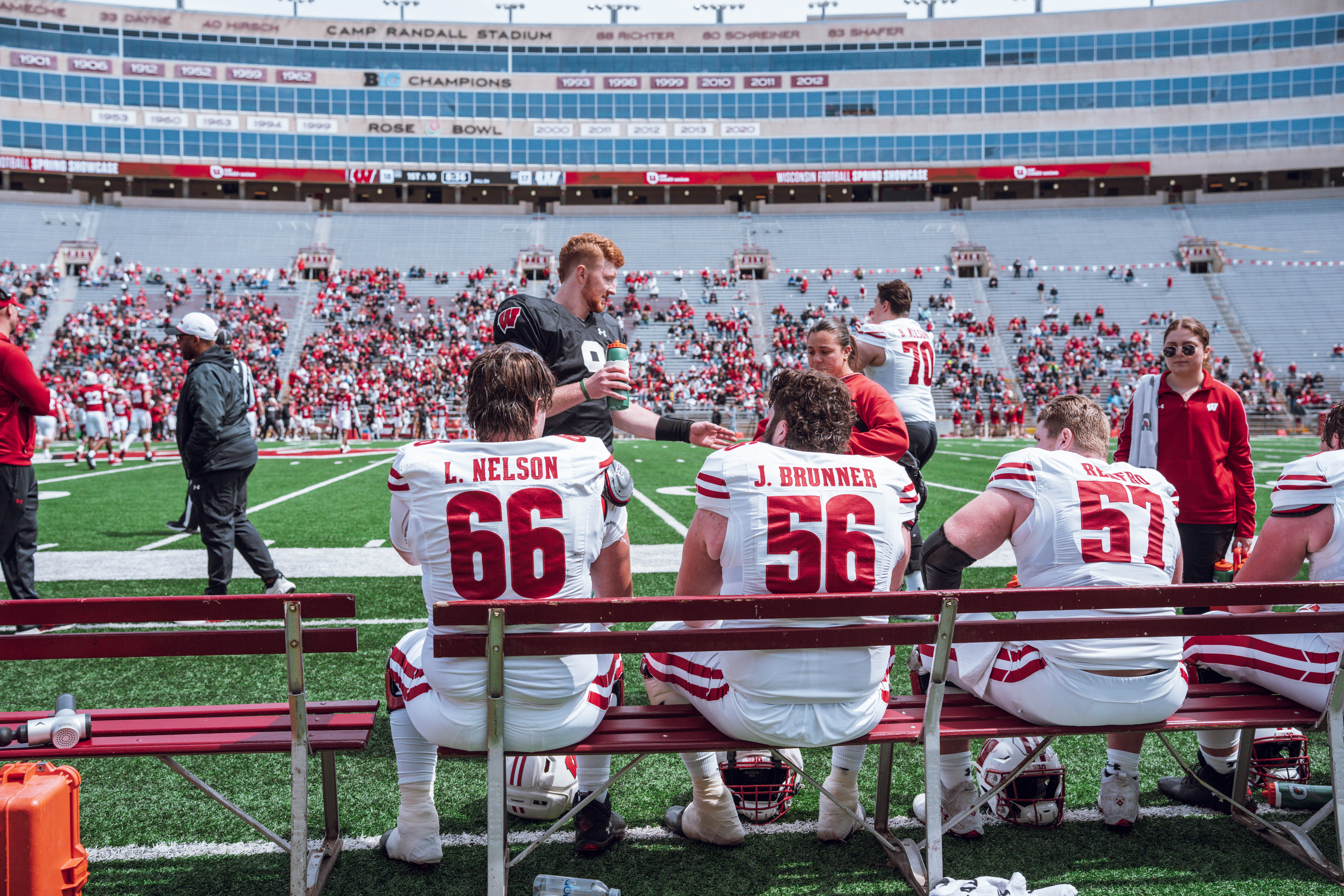 Wisconsin Badgers offensive lineman Leyton Nelson #66, Joe Brunner #56 and Jake Renfro #57 take a break while quarterback Billy Edwards Jr. #9 gets a drink during the Wisconsin Football Spring Showcase at Camp Randall Stadium on April 19, 2025 in Madison, Wisconsin. Photography by Ross Harried for Second Crop Sports.