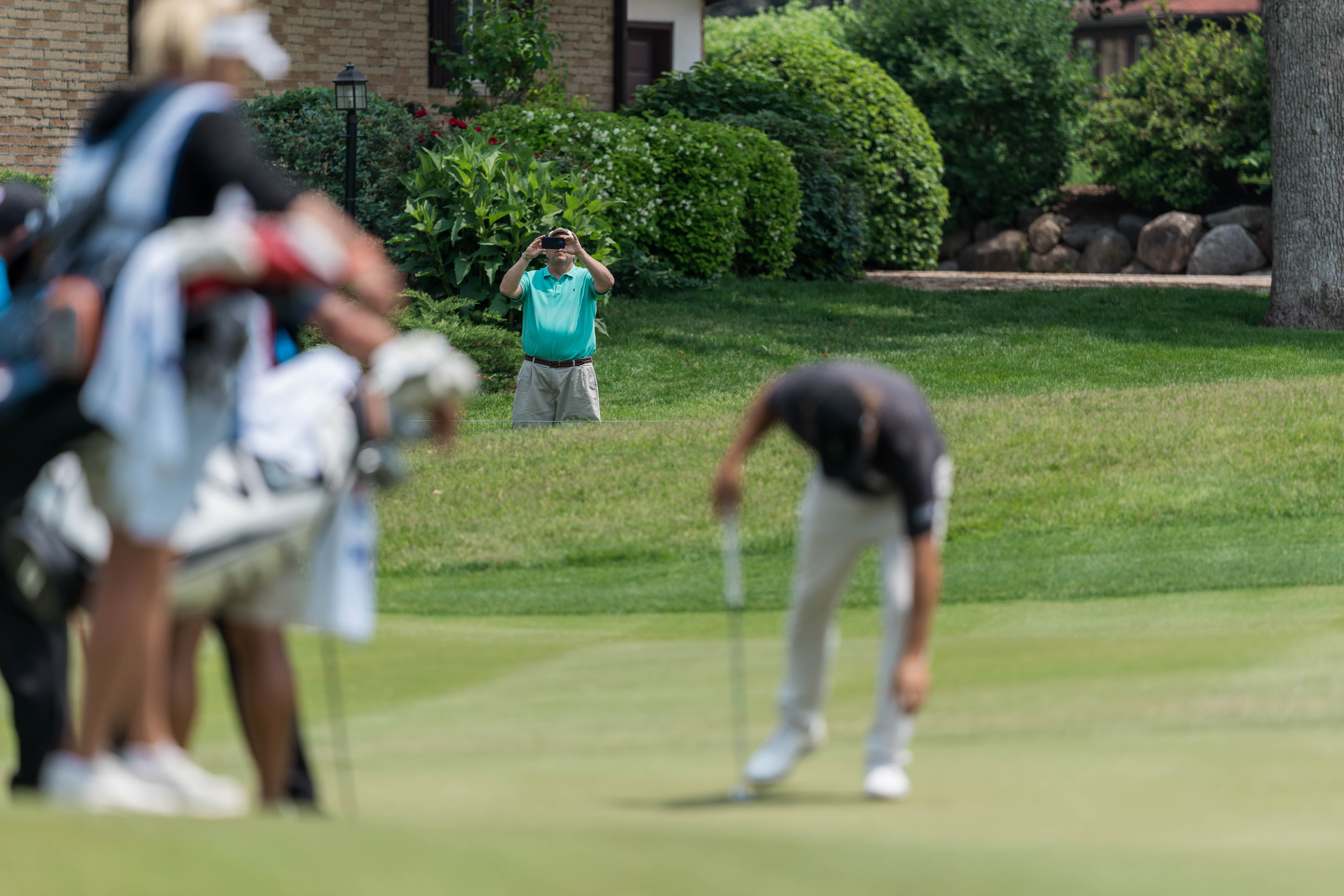 A spectator snaps a cellphone photo of Mario Tiziani retrieving his ball from the 11th hole during round 2 of The American Family Insurance Championship at TPC Wisconsin in Madison, Wisconsin on June 7th, 2025. Photography by Ross Harried for Second Crop Sports.