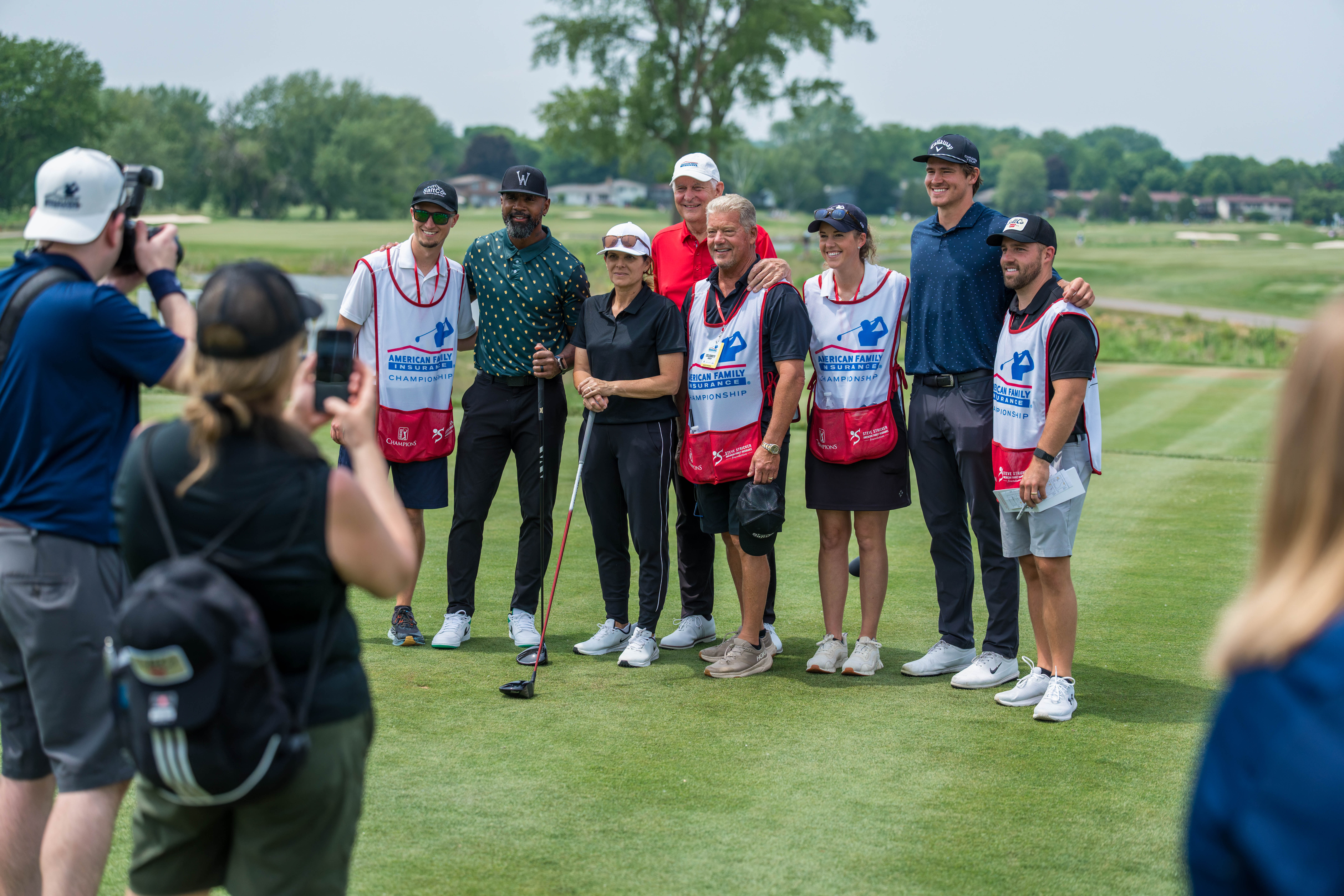 The celebrity foursome featuring Charles Woodson, Mia Hamm, Andy North and Justin Herbert pose for a photo with their caddies during round 2 of The American Family Insurance Championship at TPC Wisconsin in Madison, Wisconsin on June 7th, 2025. Photography by Ross Harried for Second Crop Sports.
