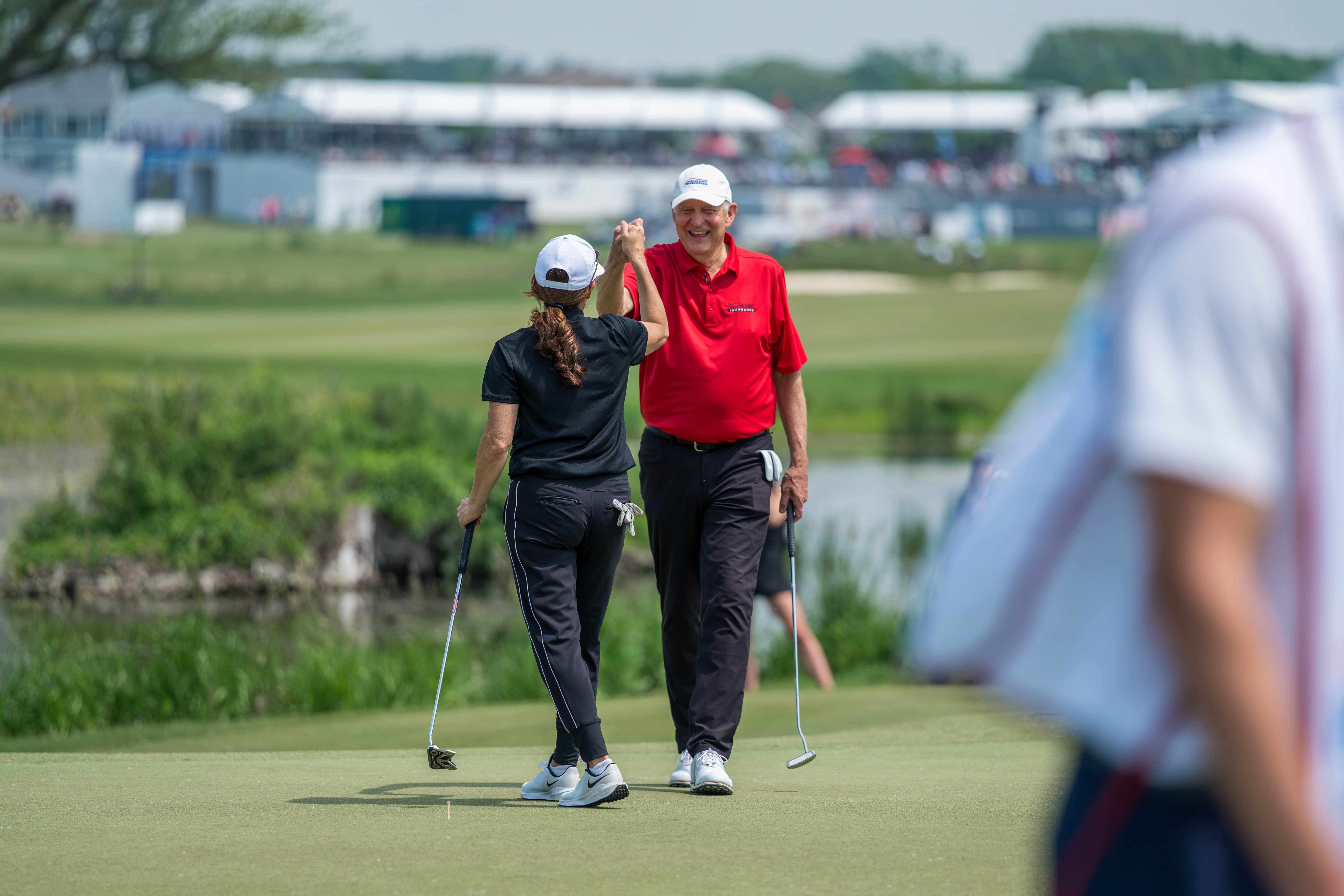 Andy North (right) gives a fist bump to Mia Hamm (left), after Mia sinks a putt on hole 1 during round 2 of The American Family Insurance Championship at TPC Wisconsin in Madison, Wisconsin on June 7th, 2025. Photography by Ross Harried for Second Crop Sports.