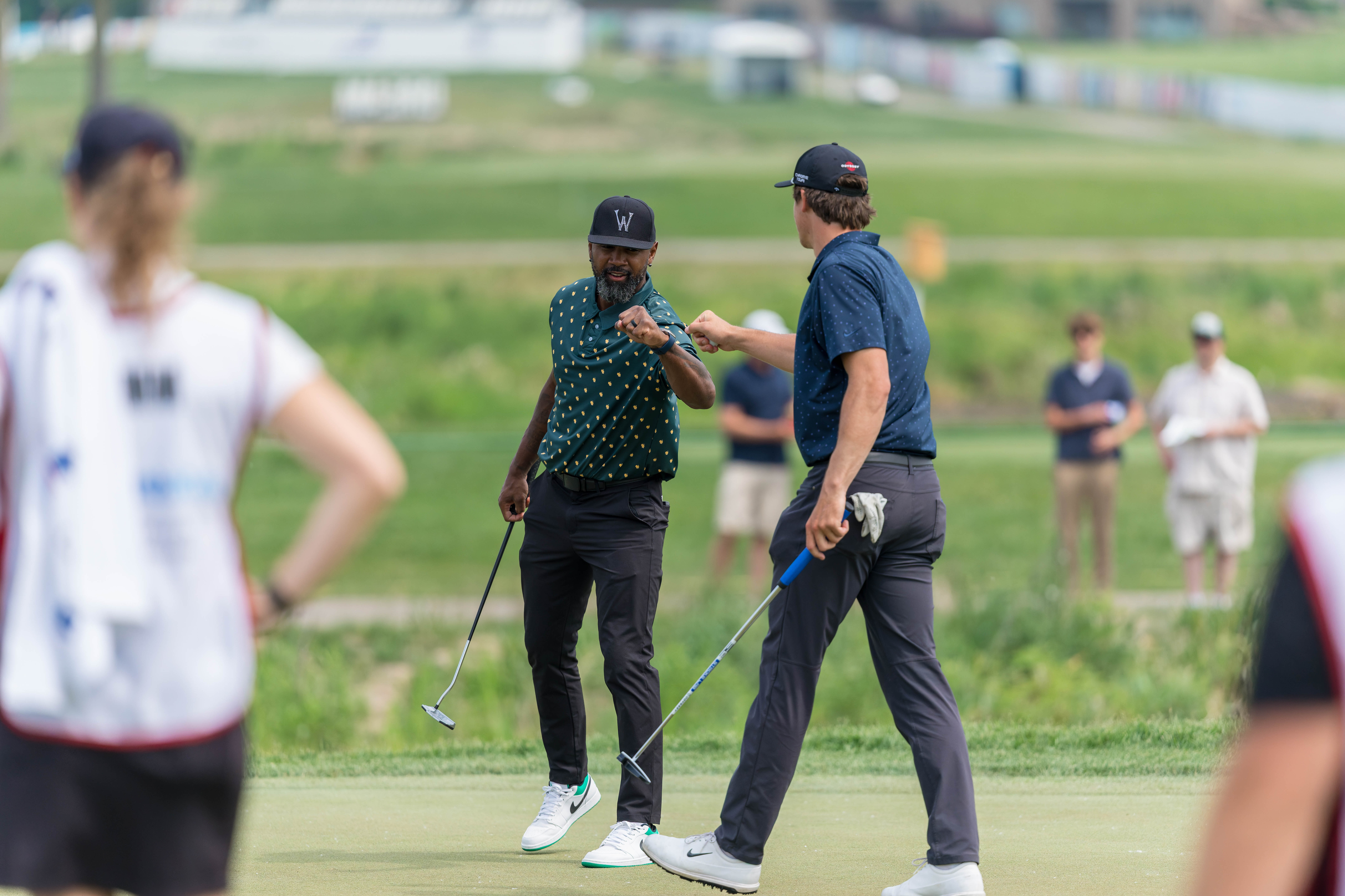 Charles Woodson (left) gives a fist bump to Justin Herbert (right) on hole 12 during round 2 of The American Family Insurance Championship at TPC Wisconsin in Madison, Wisconsin on June 7th, 2025. Photography by Ross Harried for Second Crop Sports.