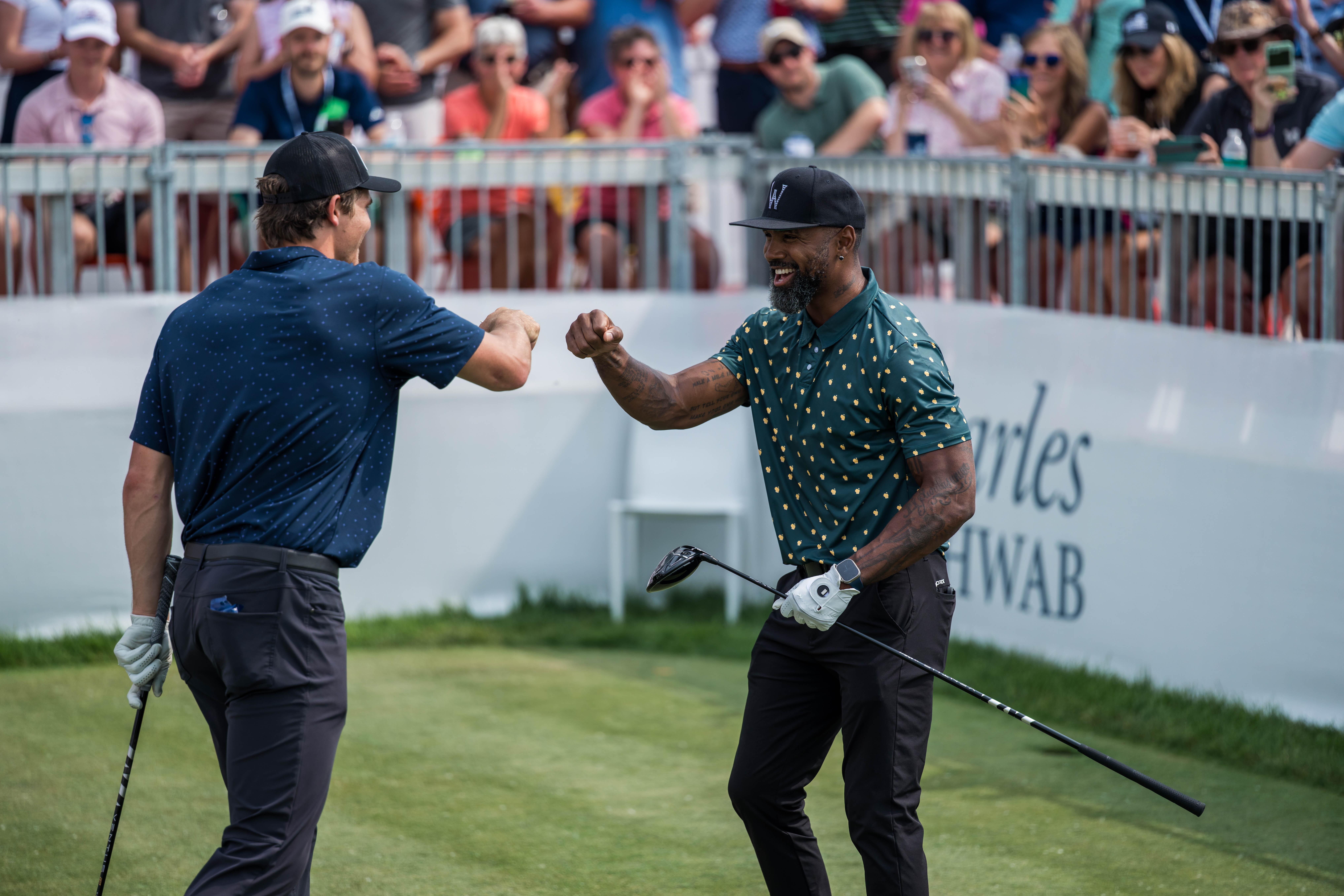 Charles Woodson (right) and Justin Herbert (left) exchanged fist bump after hitting a tee shot on the 15th hole during round 2 of The American Family Insurance Championship at TPC Wisconsin in Madison, Wisconsin on June 7th, 2025. Photography by Ross Harried for Second Crop Sports.