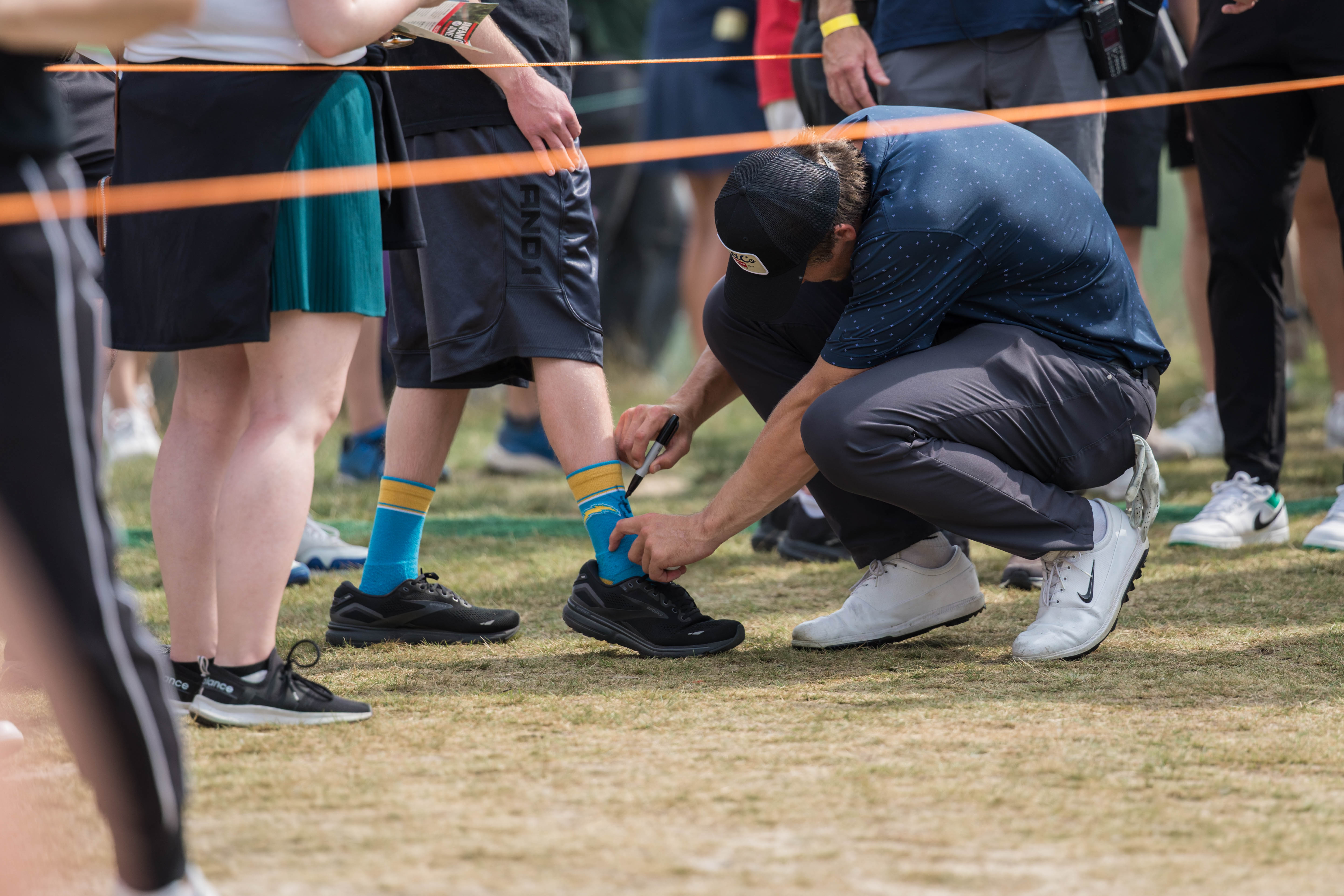 Justin Herbert signs the sock of a fan during round 2 of The American Family Insurance Championship at TPC Wisconsin in Madison, Wisconsin on June 7th, 2025. Photography by Ross Harried for Second Crop Sports.