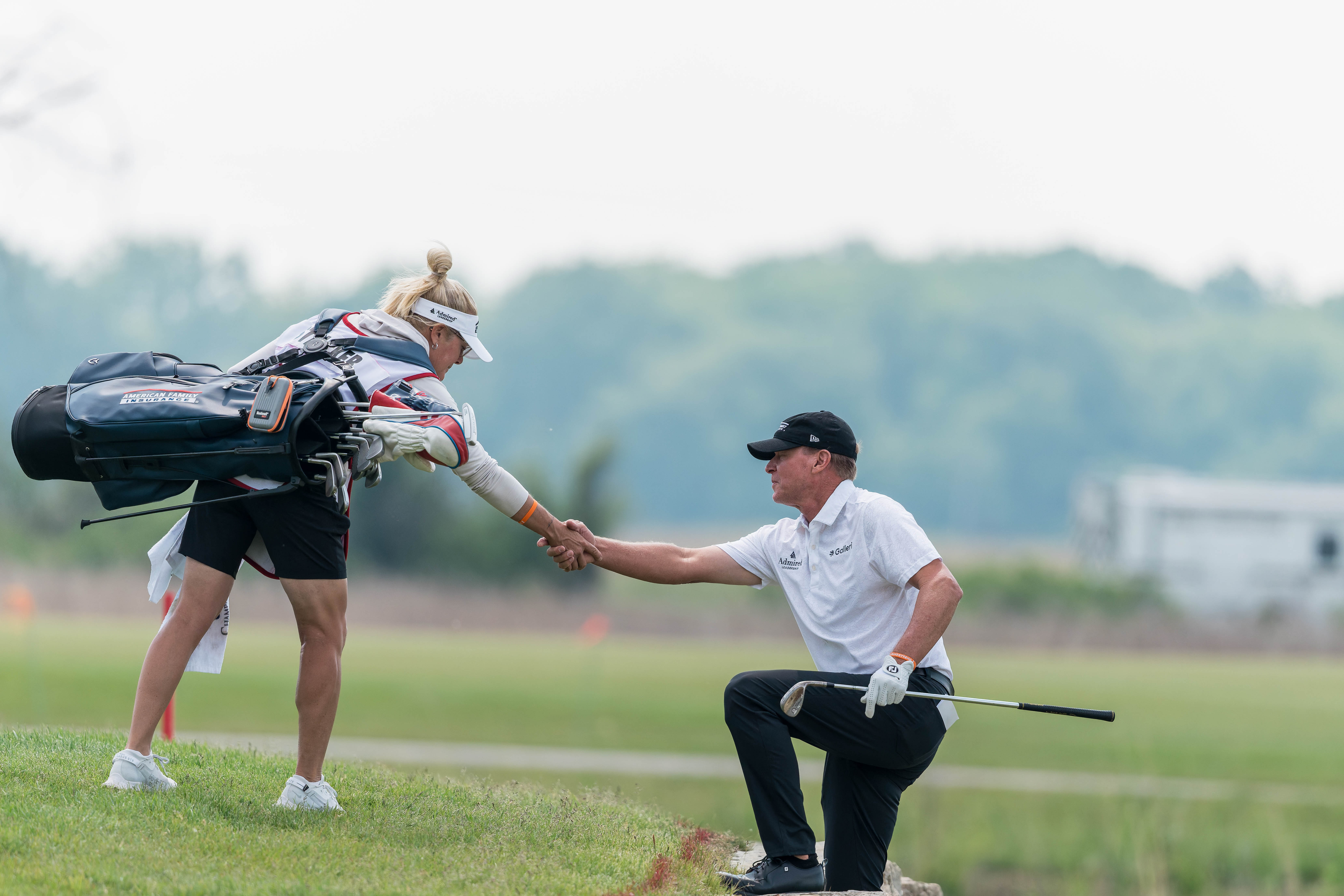 Steve Stricker climbs up a rock wall with the help of his wife and caddie, Nicki Stricker, after a hit on hole 2 during round 3 of The American Family Insurance Championship at TPC Wisconsin in Madison, Wisconsin on June 8th, 2025. Photography by Ross Harried for Second Crop Sports.