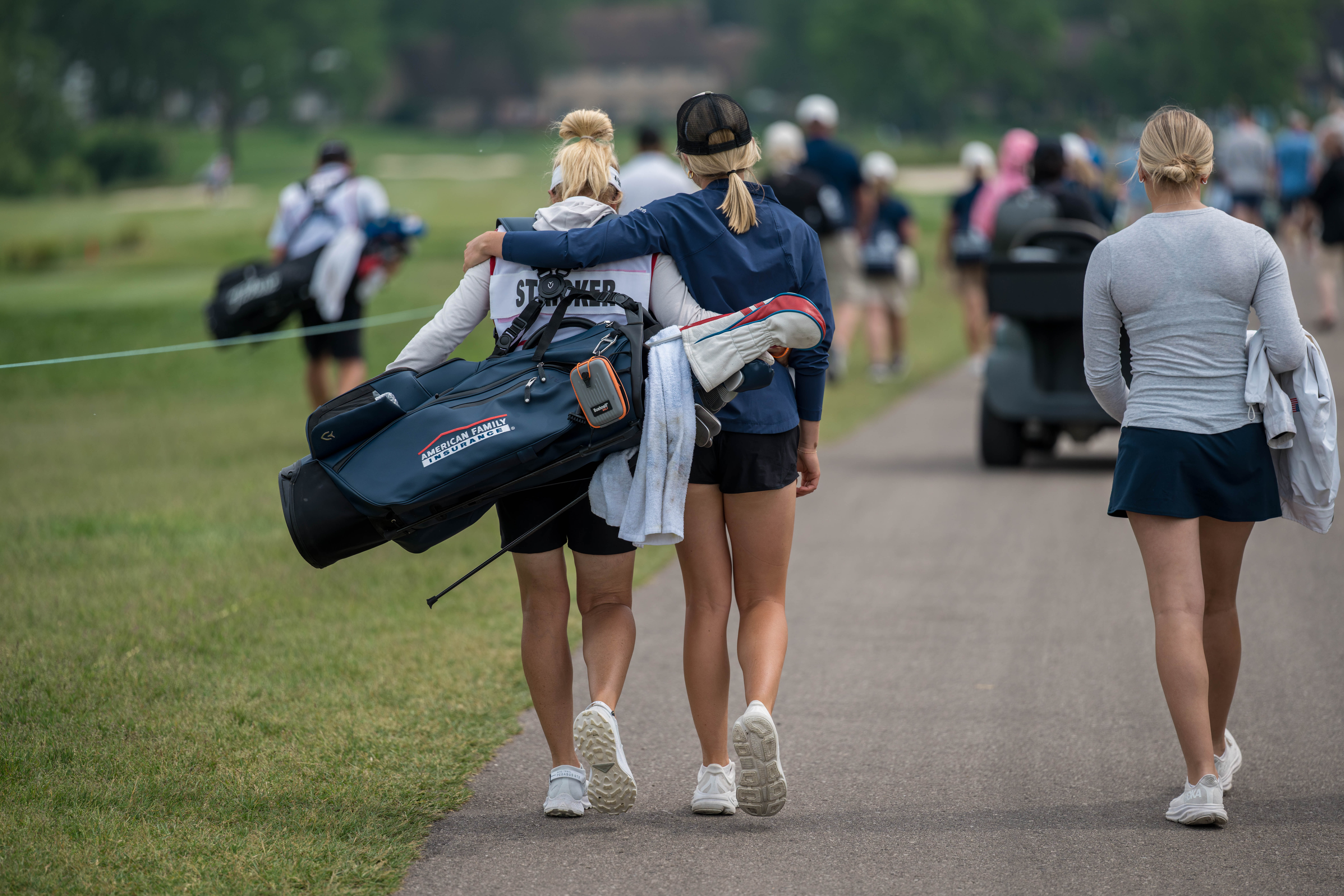 Nicki Stricker (left) caddies for husband Steve Stricker as their daughter, Izzi, embraces her during round 3 of The American Family Insurance Championship at TPC Wisconsin in Madison, Wisconsin on June 8th, 2025. Photography by Ross Harried for Second Crop Sports.