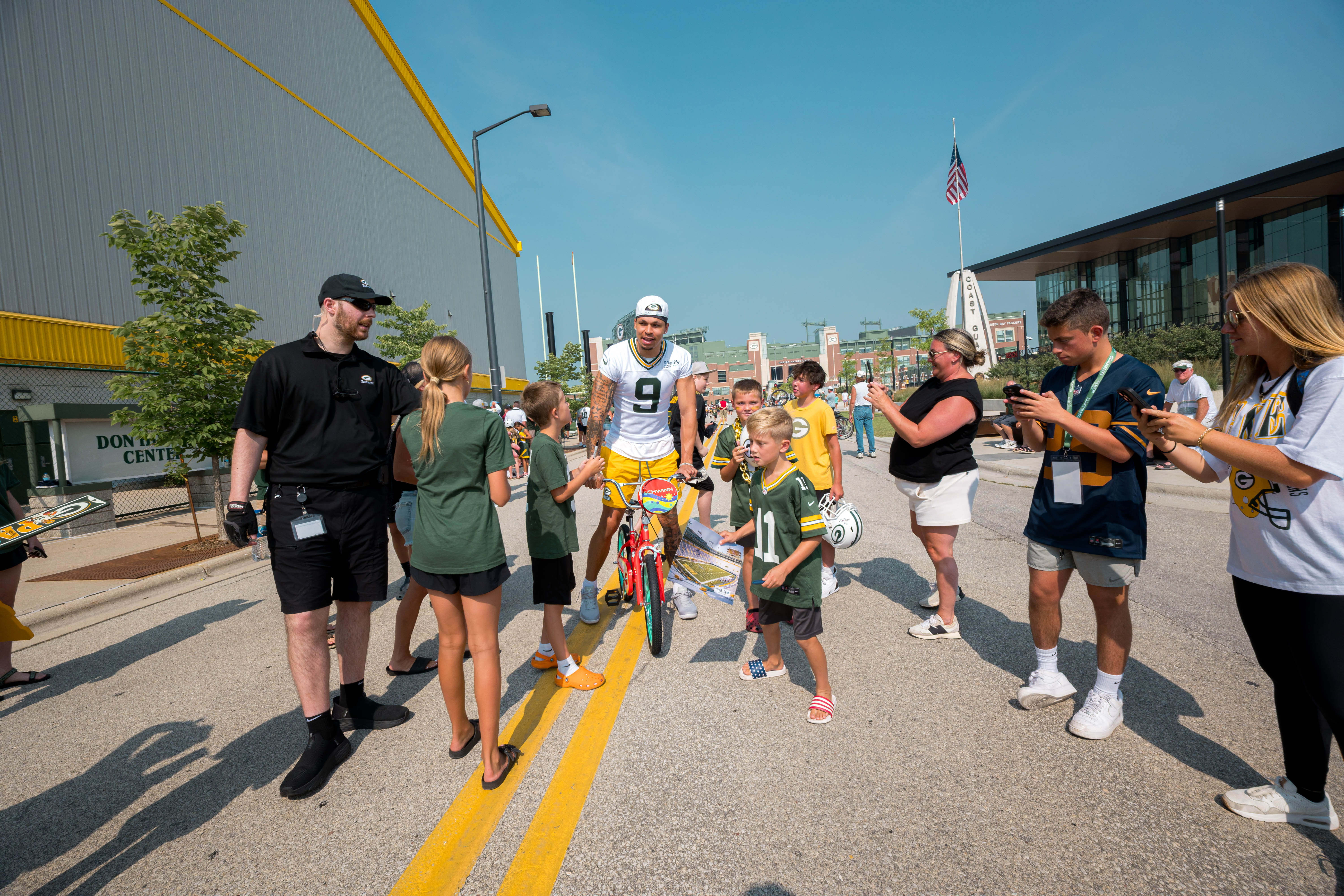 Green Bay Packers wide receiver Christian Watson rides a bicycle with fans during the team’s DreamDrive tradition at training camp in Green Bay, Wisconsin, on August 6th, 2025. Photography by Ross Harried for Second Crop Sports.