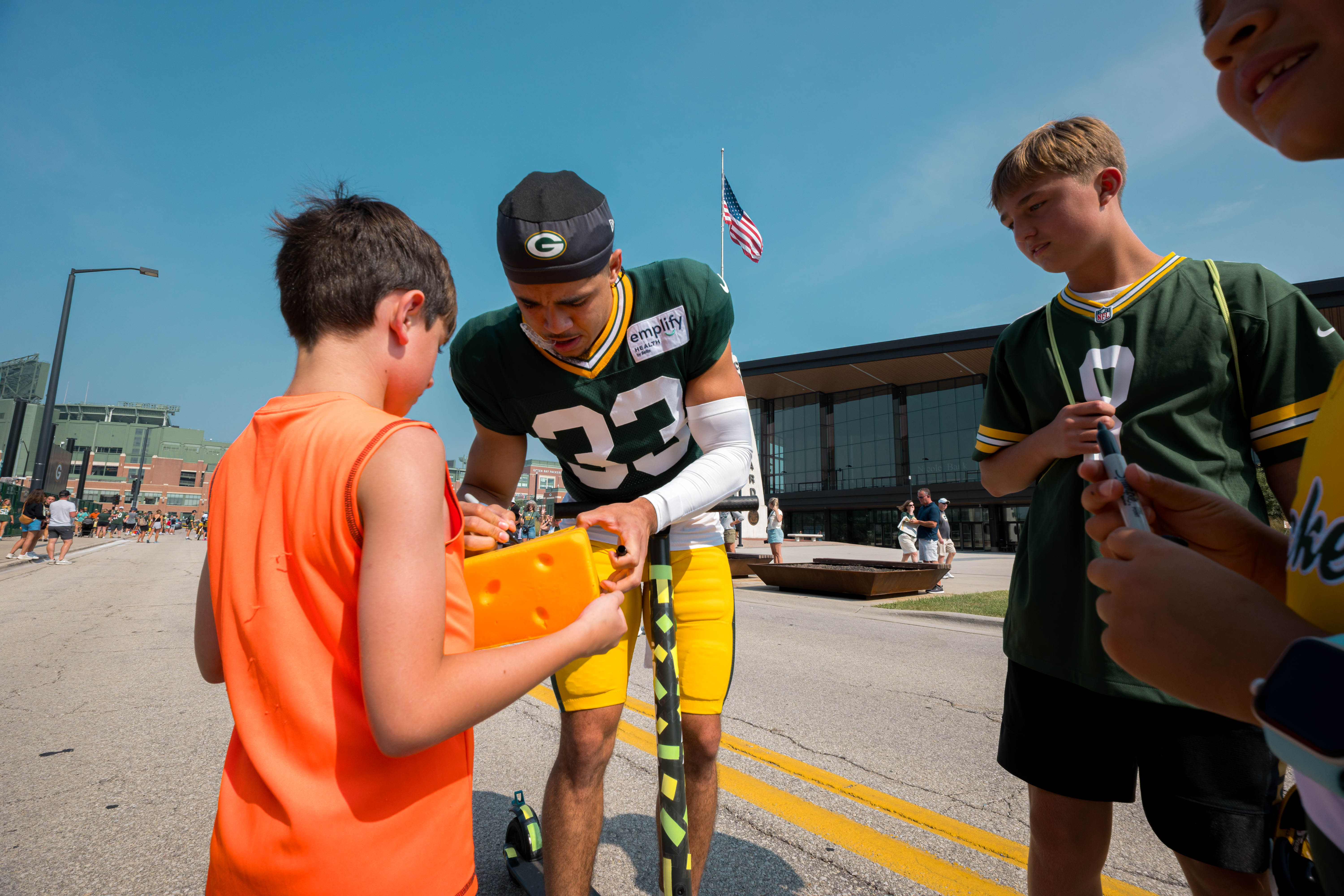 Green Bay Packers safety Evan Williams (33) signs a foam cheesehead for a young fan during training camp in Green Bay, Wisconsin, on August 6th, 2025. Photography by Ross Harried for Second Crop Sports.
