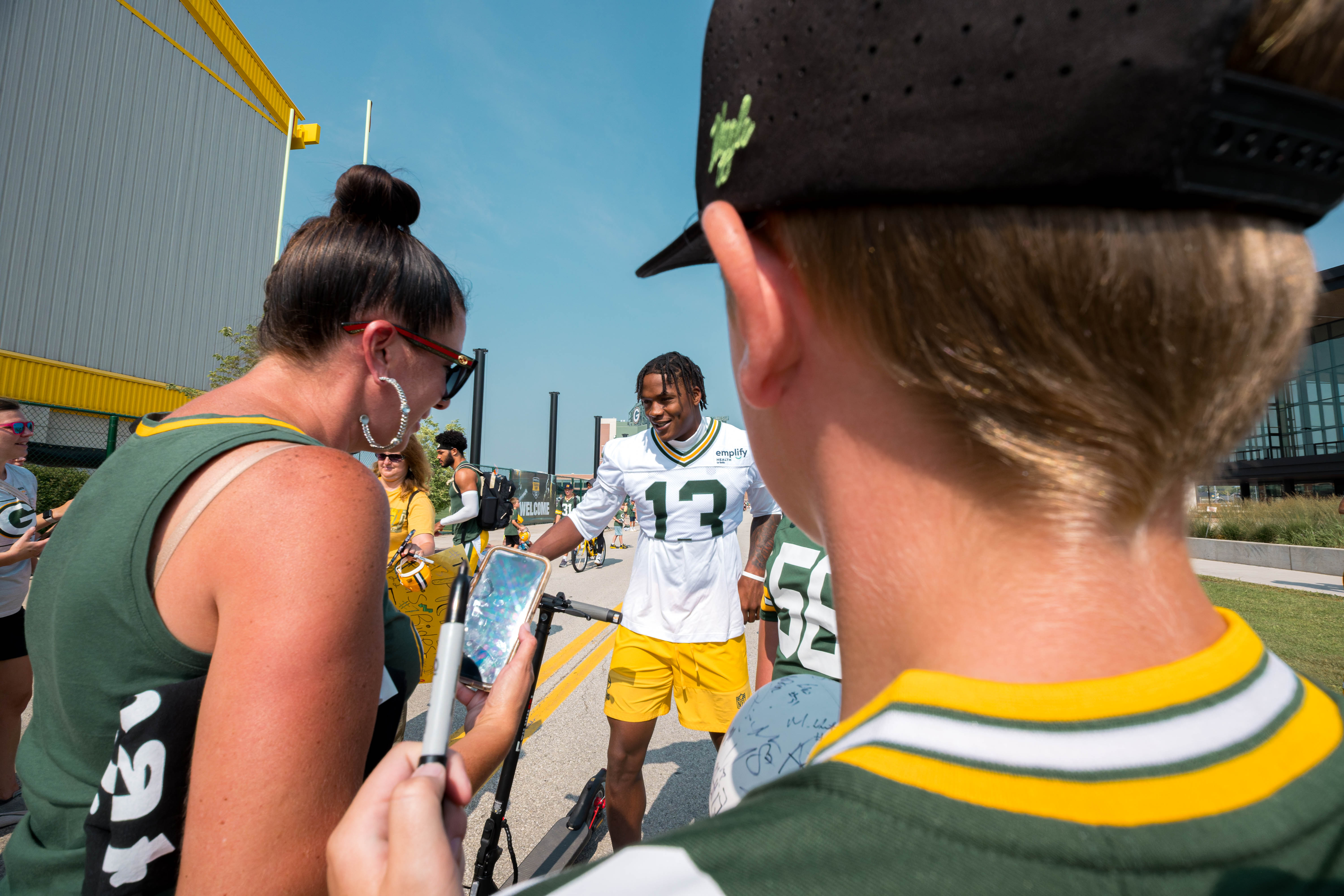 Green Bay Packers wide receiver Dontayvion Wicks (13) interacts with fans during the DreamDrive tradition at training camp in Green Bay, Wisconsin, on August 6th, 2025. Photography by Ross Harried for Second Crop Sports.